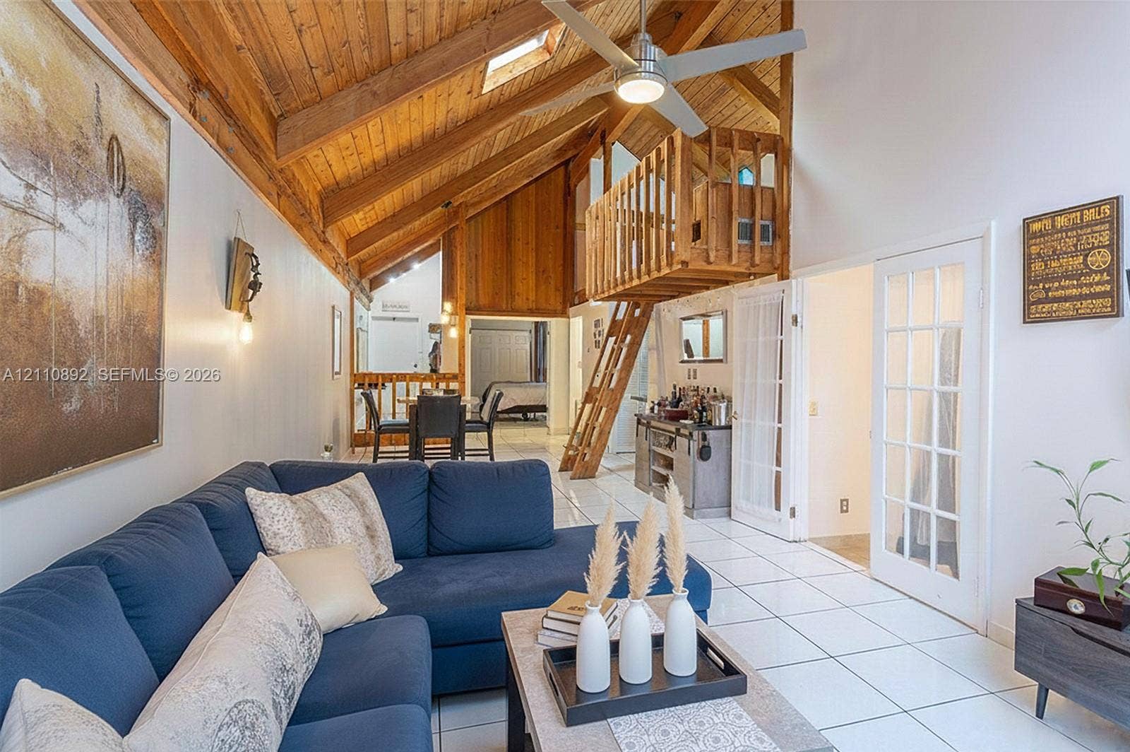 497 N University Drive, #2-7, Plantation, FL 33324 Vaulted timber-plank ceiling featuring exposed beams, skylight, wooden loft structure with integrated ladder, tile flooring, and French doors with glass panes