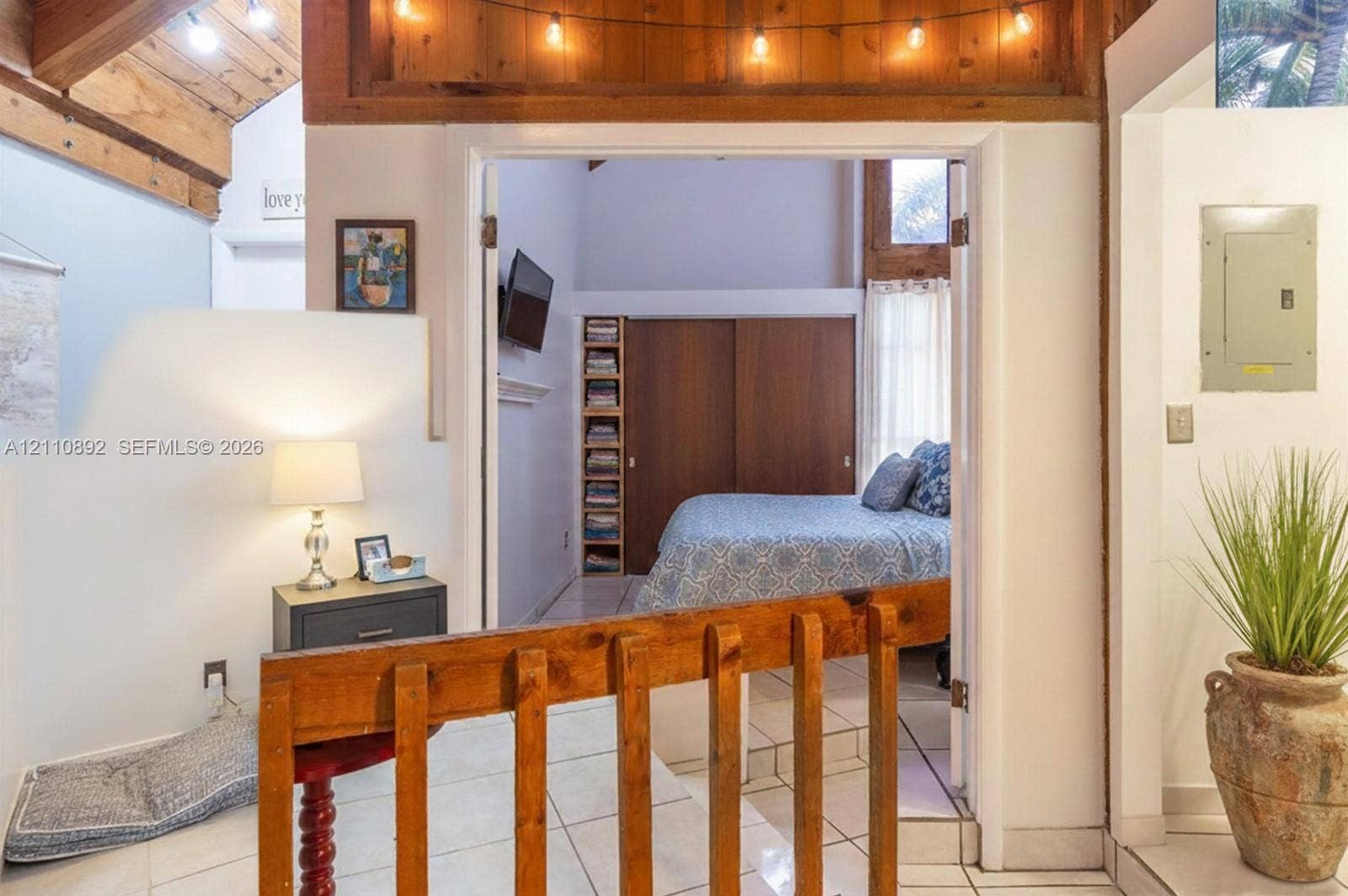 497 N University Drive, #2-7, Plantation, FL 33324 Exposed wood ceiling beams, white ceramic tile flooring, floor-to-ceiling wooden built-in shelving, sliding wood closet doors, and wood-railing partition