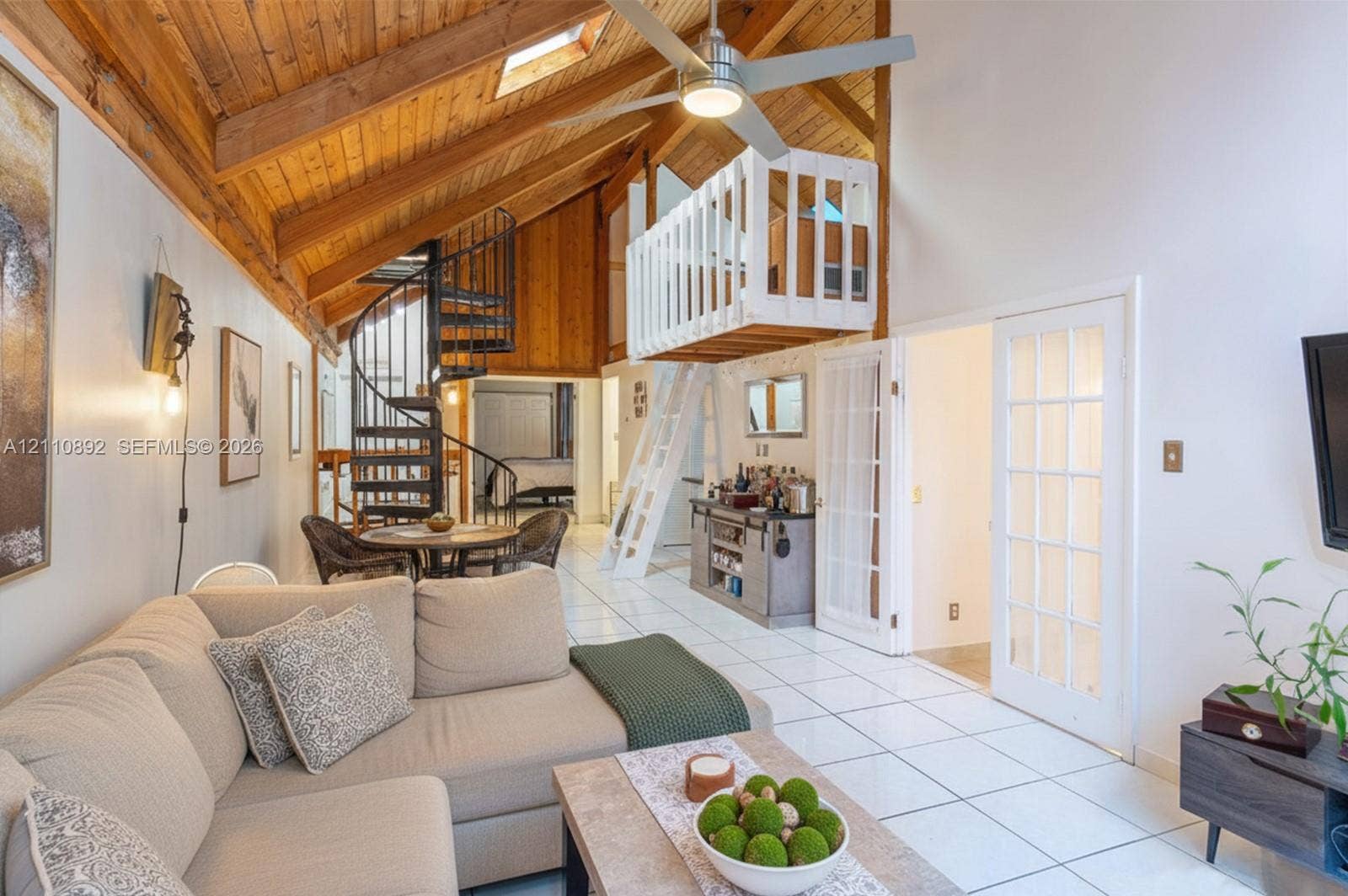 497 N University Drive, #2-7, Plantation, FL 33324 Vaulted wood-paneled ceiling with skylight, exposed wooden beams, metal spiral staircase, white-railed loft level, and French doors with glass panes