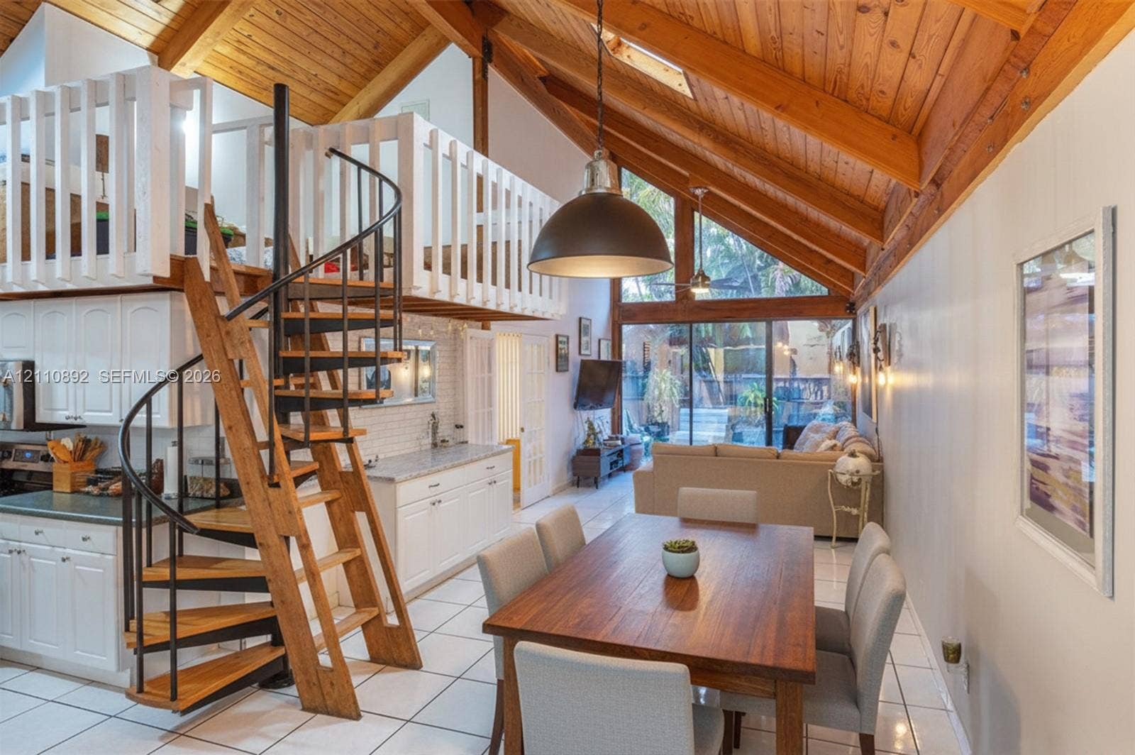 497 N University Drive, #2-7, Plantation, FL 33324 Vaulted wood-paneled ceilings, floor-to-ceiling glass paneling, white built-in cabinetry, custom metal and wood-finished spiral staircase, and lofted upper level