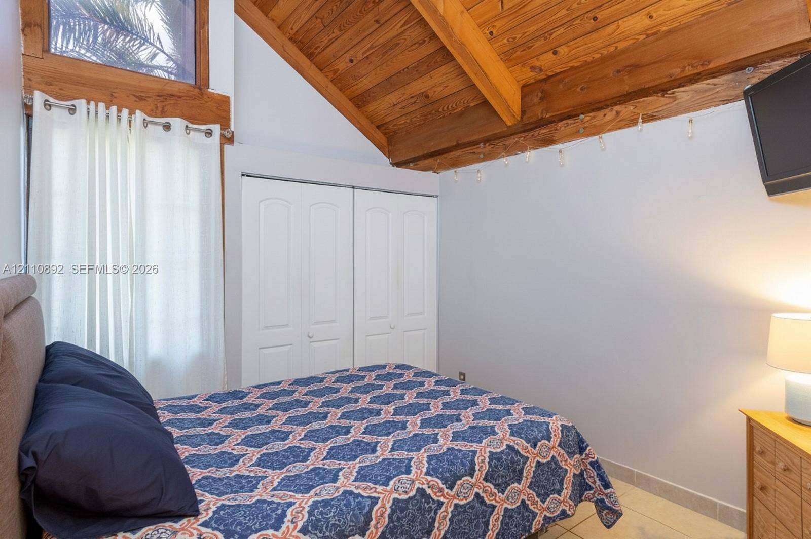 497 N University Drive, #2-7, Plantation, FL 33324 Vaulted ceiling with exposed wood beams, natural wood window trim, tile flooring, and built-in closet with double doors