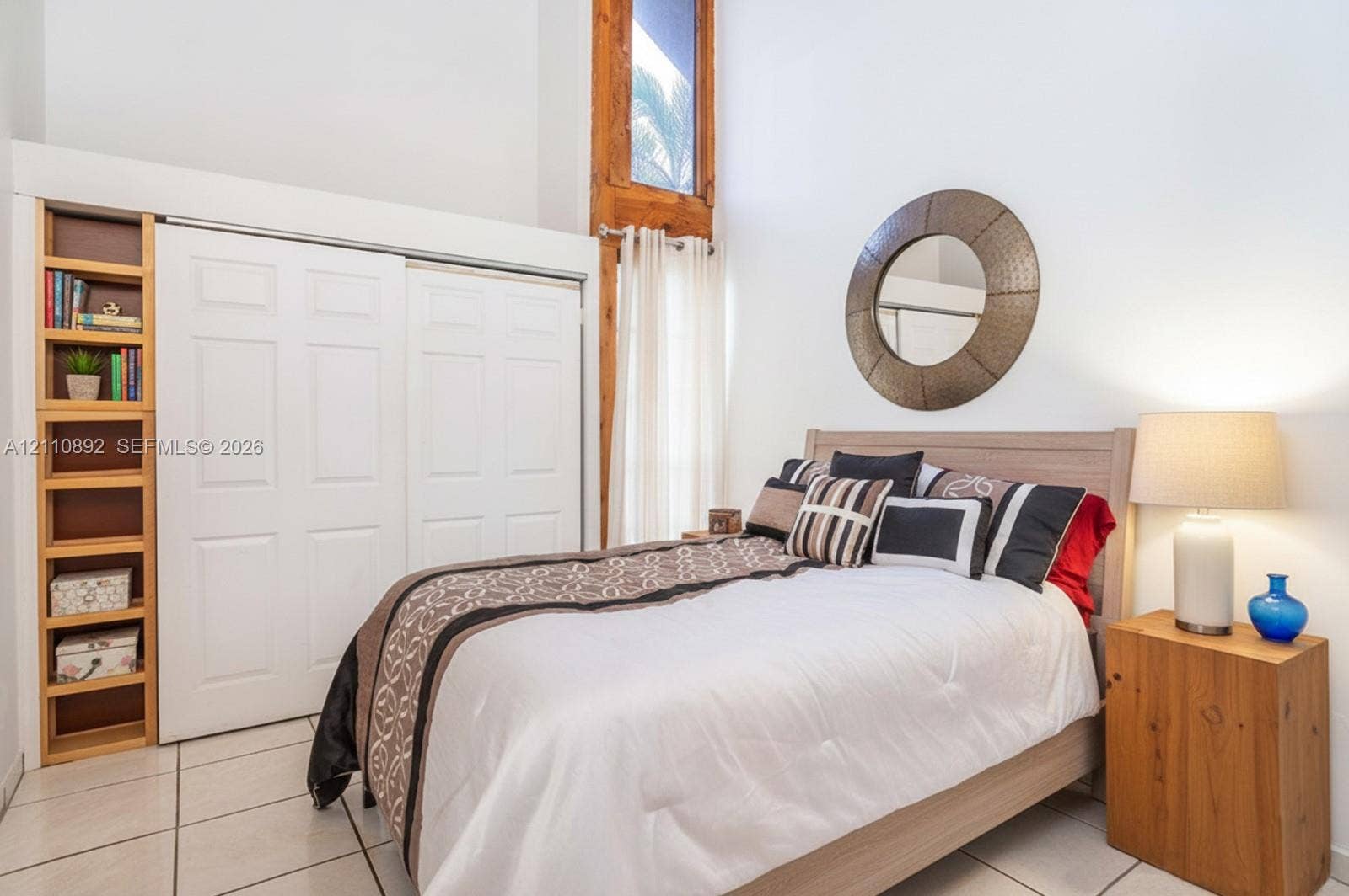497 N University Drive, #2-7, Plantation, FL 33324 Vaulted ceilings with natural wood-trimmed vertical window, floor-to-ceiling built-in shelving, white paneled sliding closet doors, and ceramic tile flooring