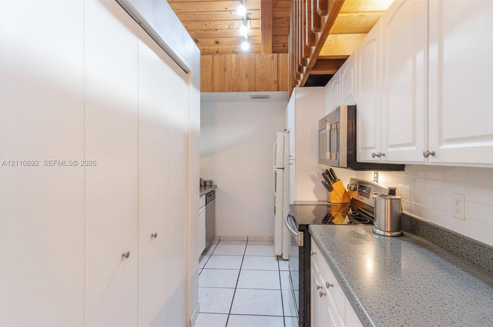 497 N University Drive, #2-7, Plantation, FL 33324 Kitchen featuring white cabinetry, solid-surface countertops, a tiled backsplash, wood-plank ceiling, and floor tiles
