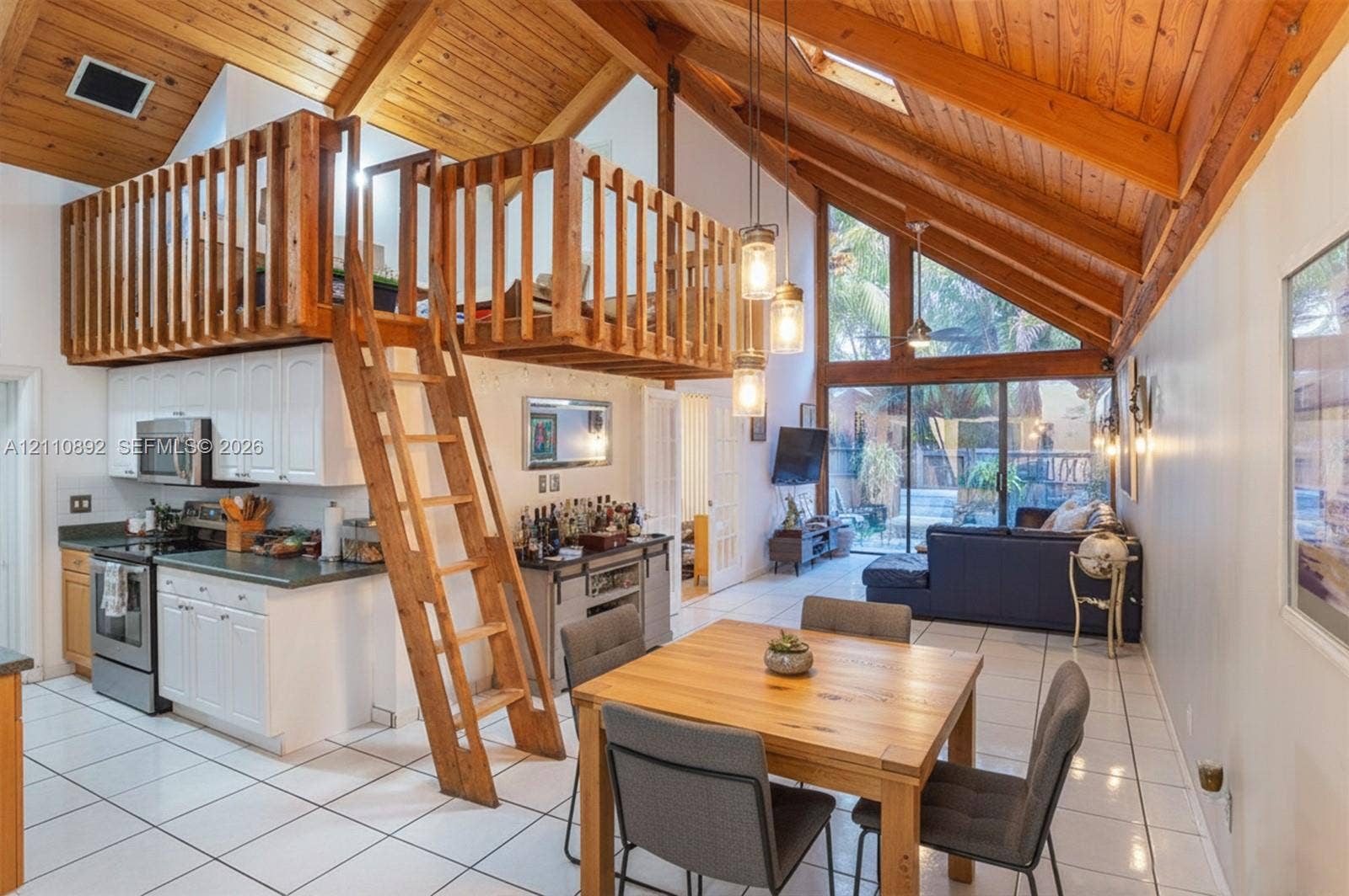 497 N University Drive, #2-7, Plantation, FL 33324 Vaulted wood-plank ceiling featuring exposed beams, mezzanine level with wooden railings, floor-to-ceiling glass paneling, tile flooring, and integrated pendant lighting