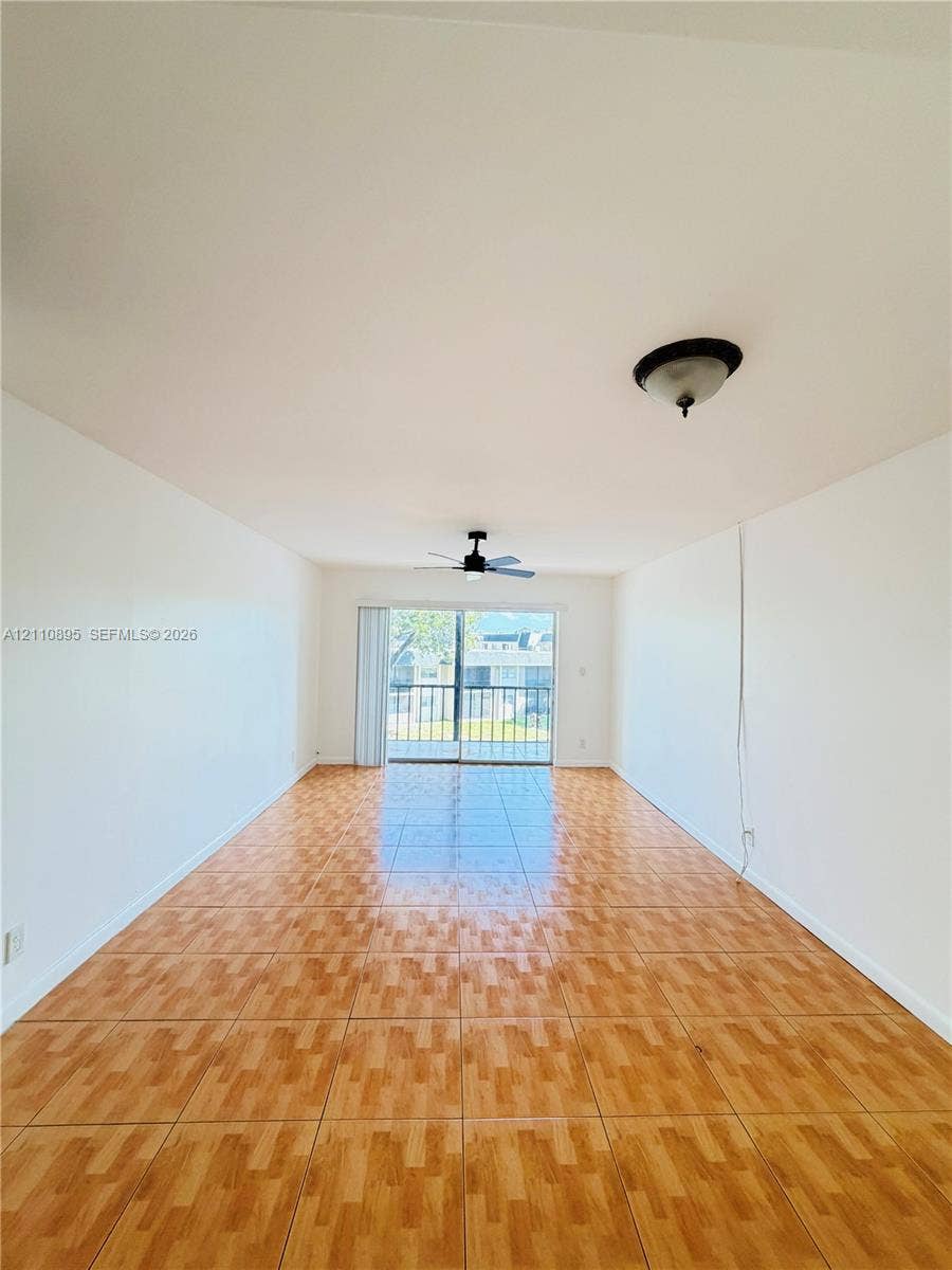 Interior space featuring tile flooring, ceiling fan with light fixture, flush-mount lighting, and sliding glass door with access to a balcony