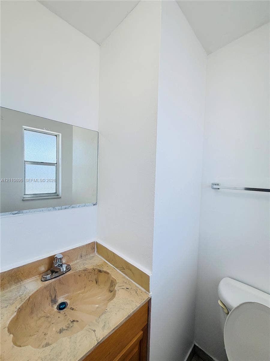 Integrated vanity featuring a stone-patterned countertop, an oval-molded sink, a polished metal faucet, and a wall-mounted rectangular mirror