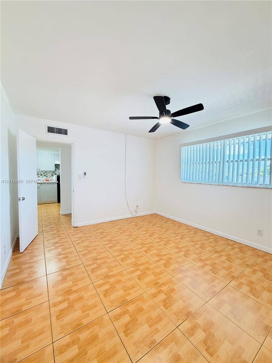 Room featuring wood-finish tile flooring, a multi-blade ceiling fan with integrated lighting, and vertical window blinds