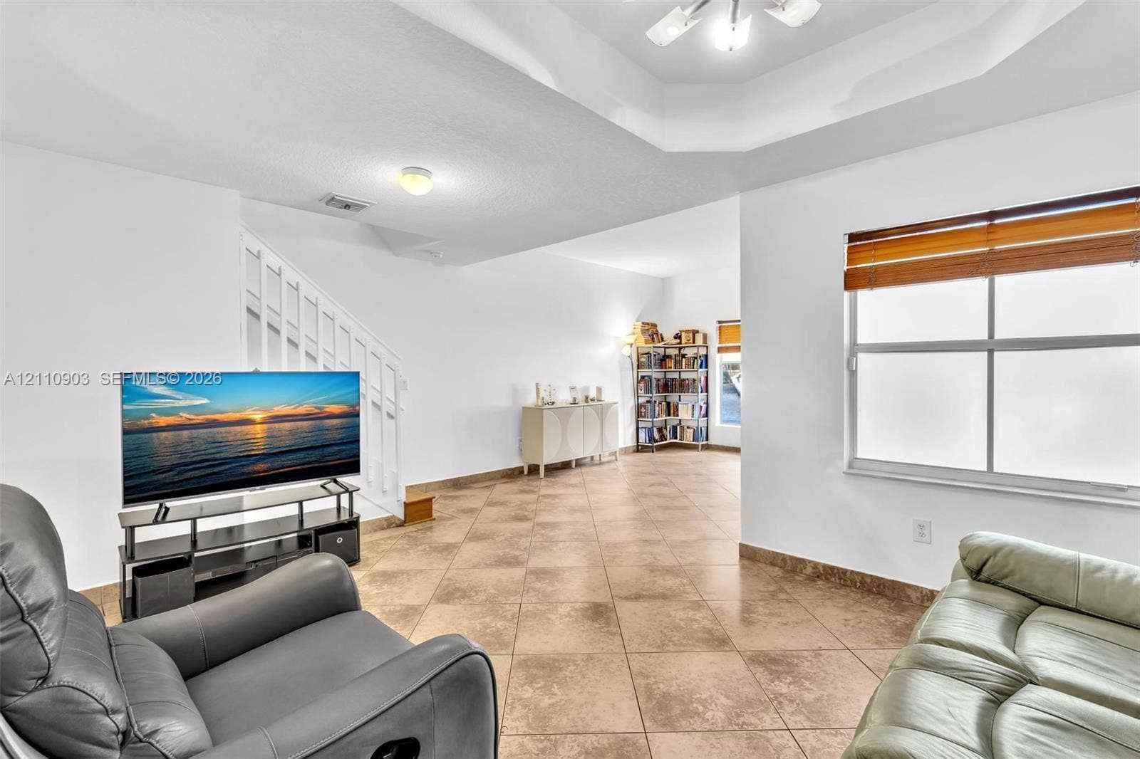Tray ceiling, ceramic tile flooring, and staircase with white railings