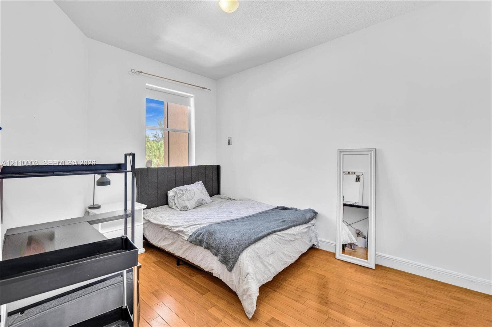 Room with wood-finish flooring, white walls, and a single-pane window
