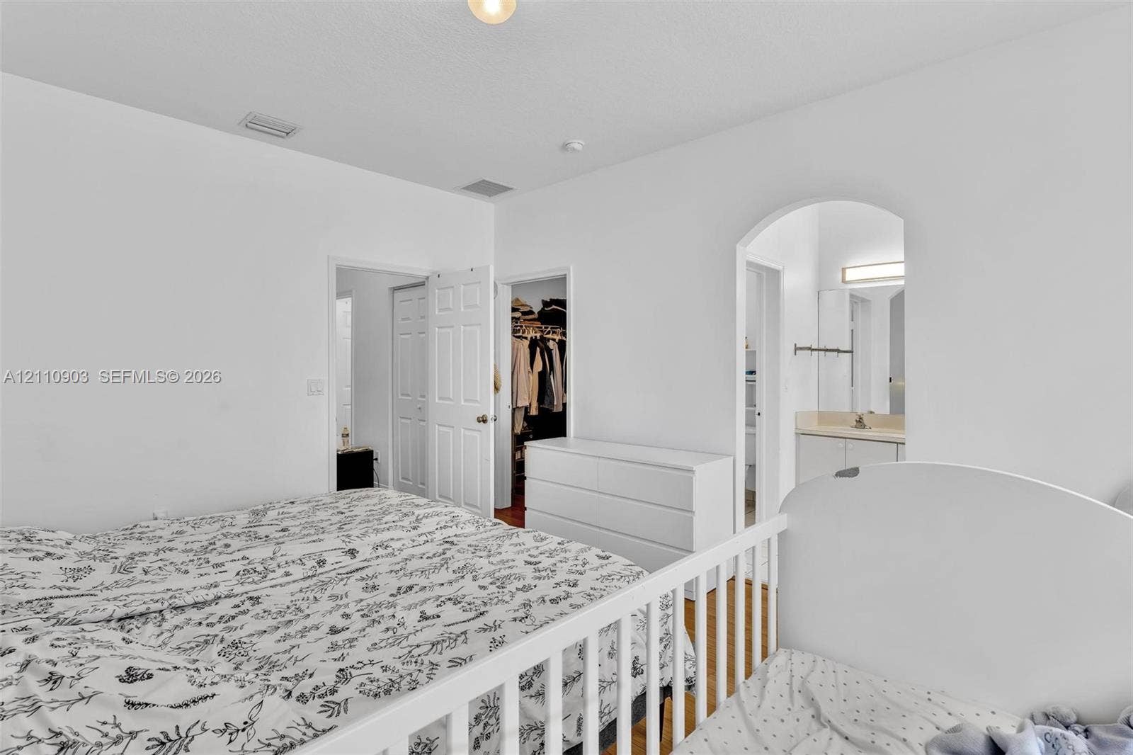 Neutral-toned interior space featuring high ceilings, a classic arched doorway, and white paneled interior doors