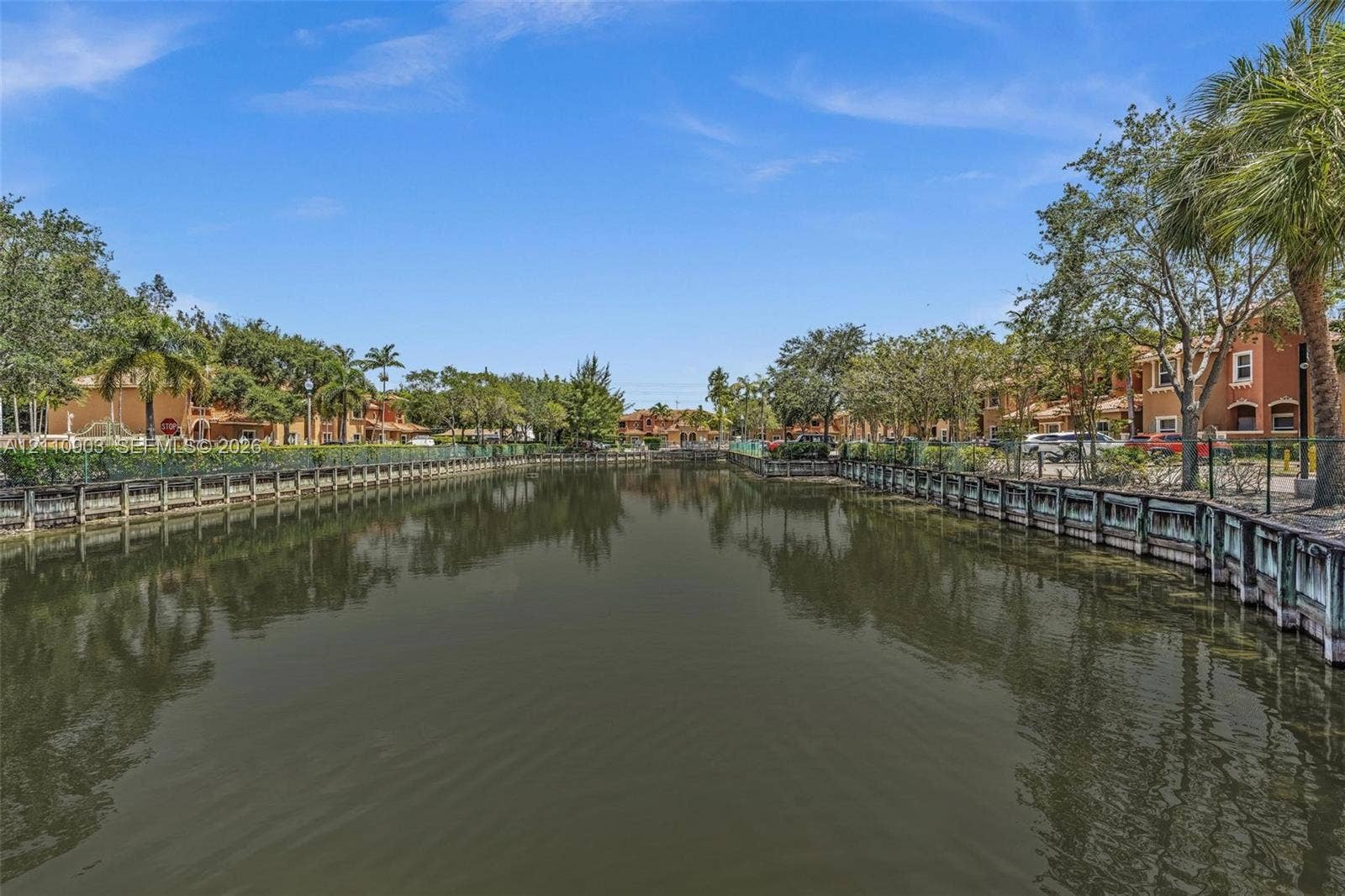 Waterfront setting featuring a concrete seawall, mature palm trees, and manicured perimeter landscaping