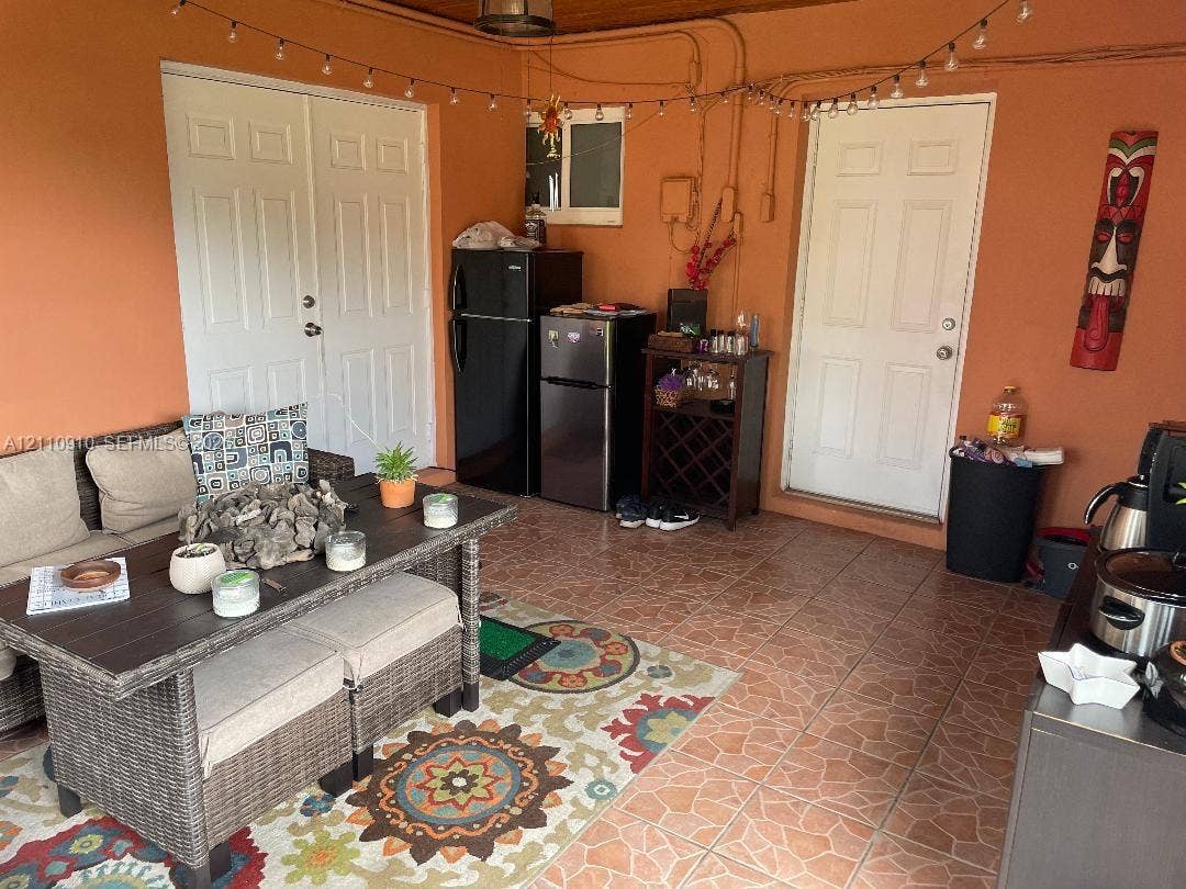 Covered patio featuring ceramic tile flooring, wood-paneled ceiling, and two sets of white-paneled entry doors