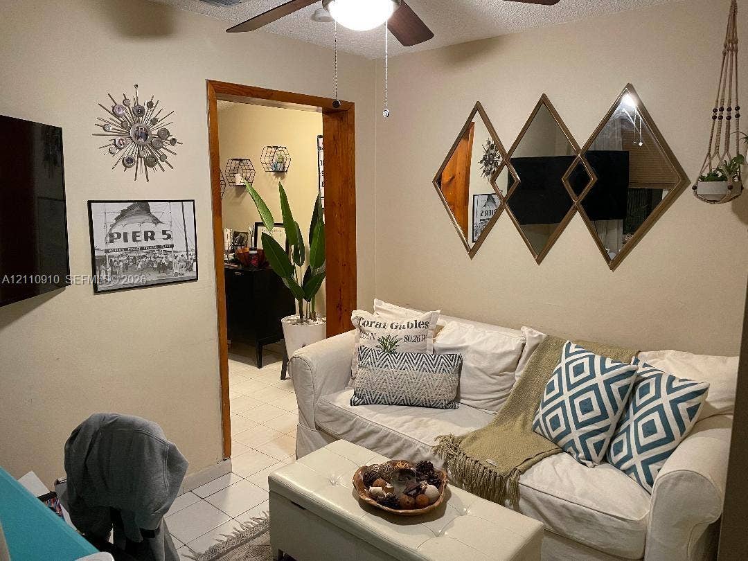 Interior space featuring ceramic tile flooring, a natural wood-trimmed doorway, and a ceiling fan with integrated lighting