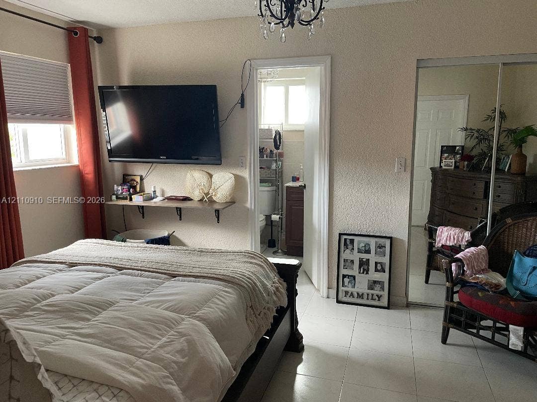 Interior space featuring ceramic tile flooring, mirrored sliding-door closet, and an ornate multi-arm chandelier