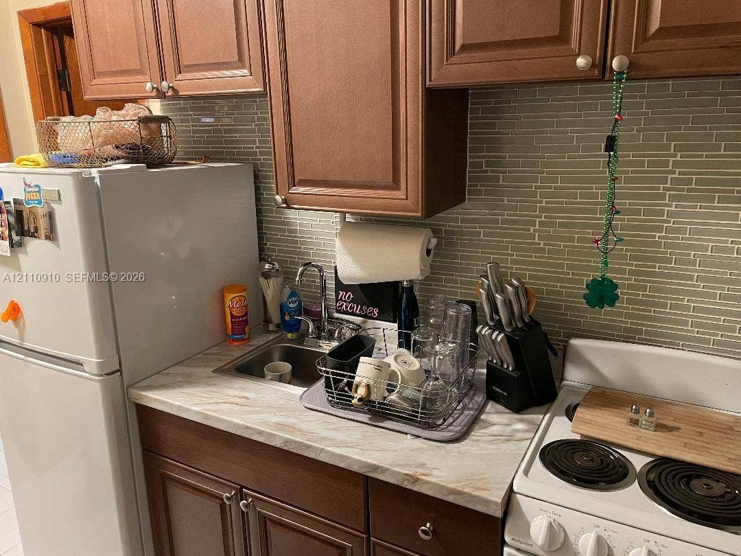 Kitchen featuring wood cabinetry, stone-pattern laminate countertops, and a linear tile backsplash