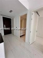 Entry foyer featuring high-gloss tile flooring, solid dark-wood entry door, and recessed lighting