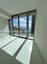 Floor-to-ceiling glass sliding doors, large-format tile flooring, and metal-framed windows featuring coastal scenery