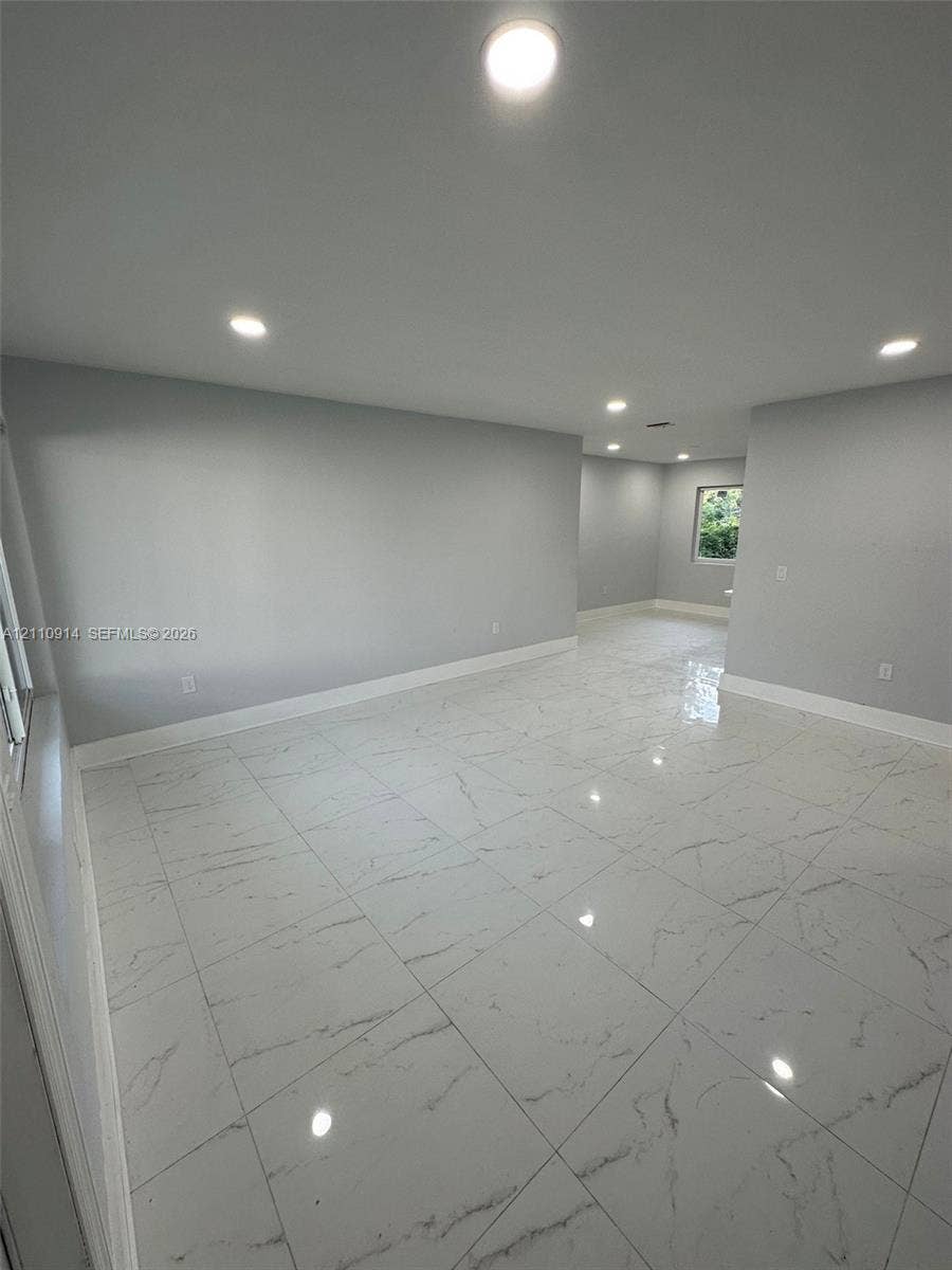 Interior space featuring light-toned neutral walls, large-format polished tile flooring with marble-style veining, and recessed ceiling lighting