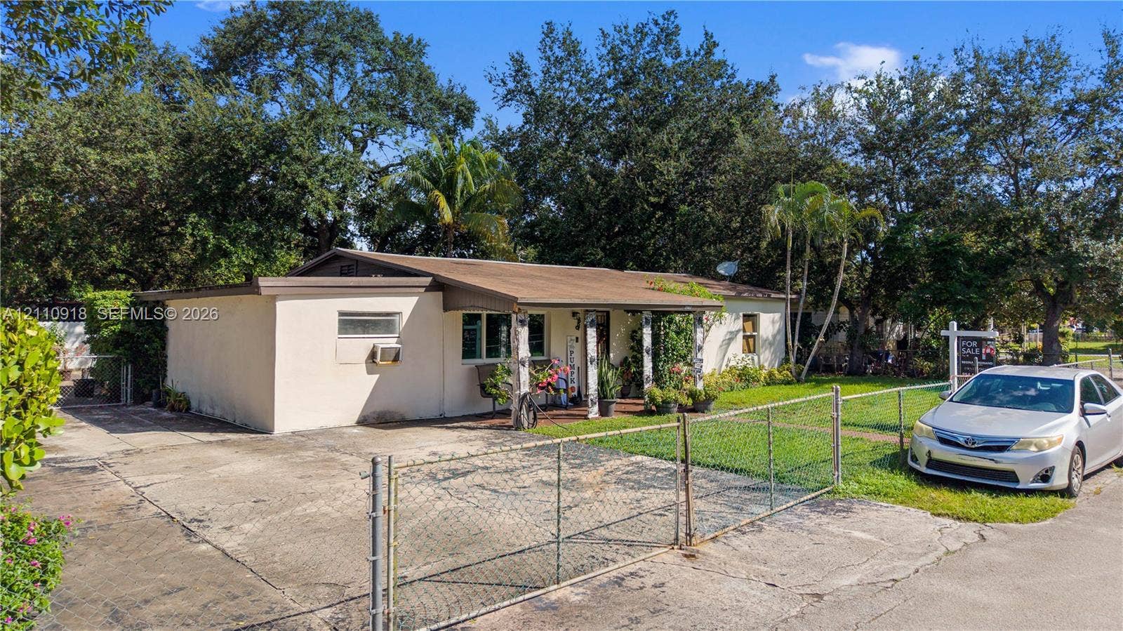 2007 NW 89th Street, Miami, FL 33147 Single-story exterior featuring a concrete driveway, metal chain-link fencing, and a covered entryway
