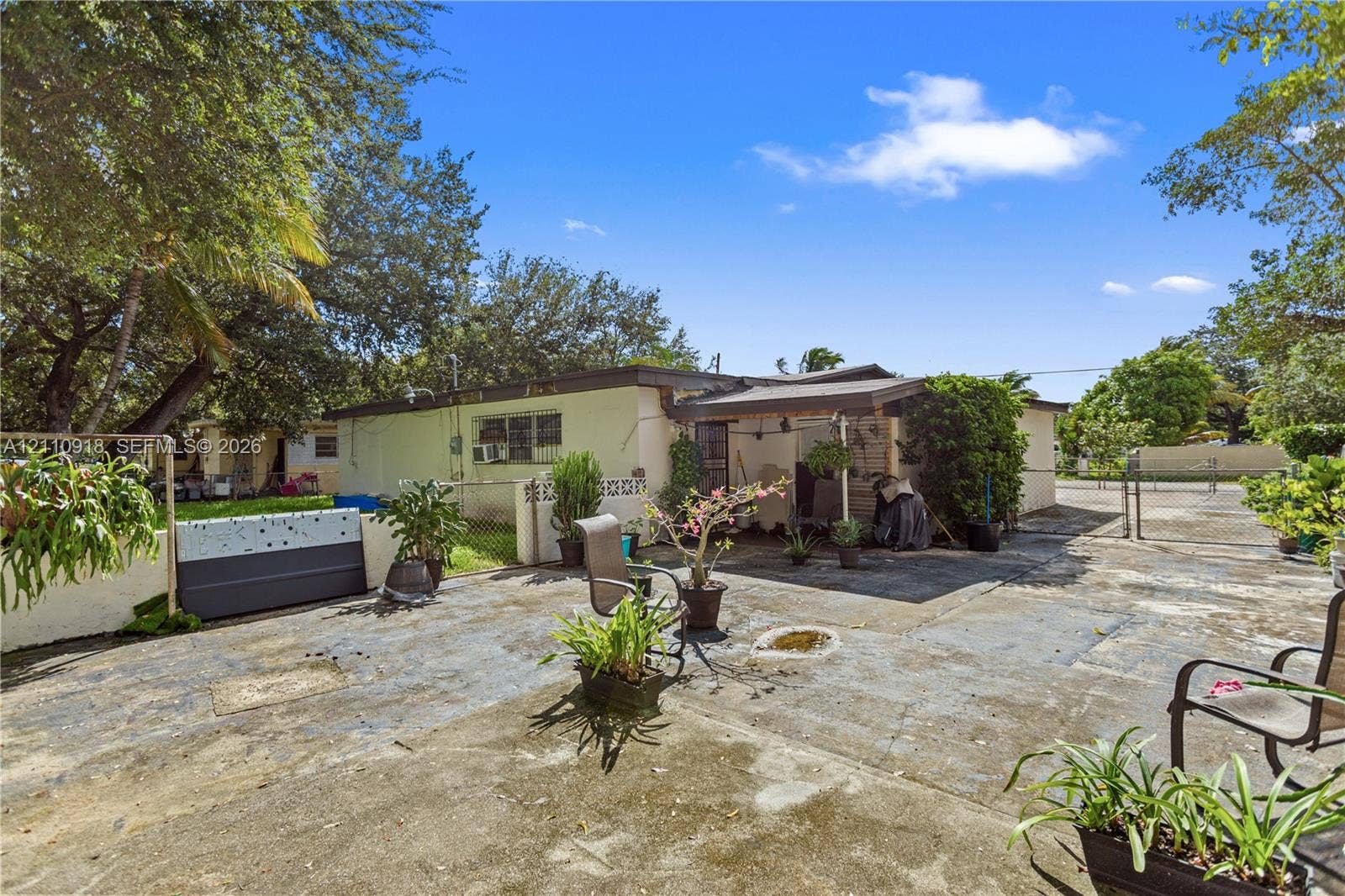 2007 NW 89th Street, Miami, FL 33147 Exterior area featuring a concrete patio, a covered porch, perimeter fencing, and mature trees