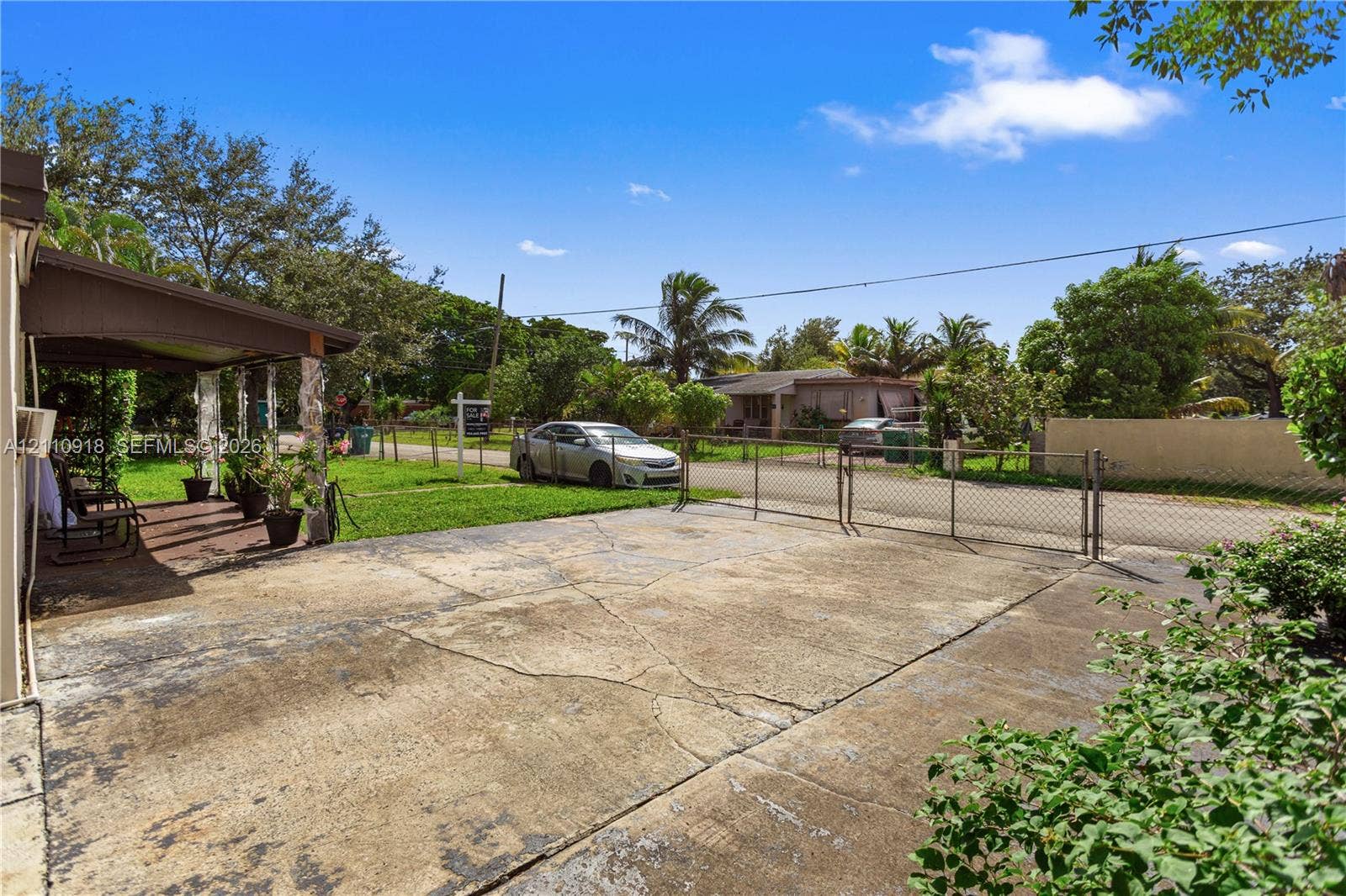 2007 NW 89th Street, Miami, FL 33147 Concrete driveway, chain-link perimeter fencing, and covered outdoor patio area