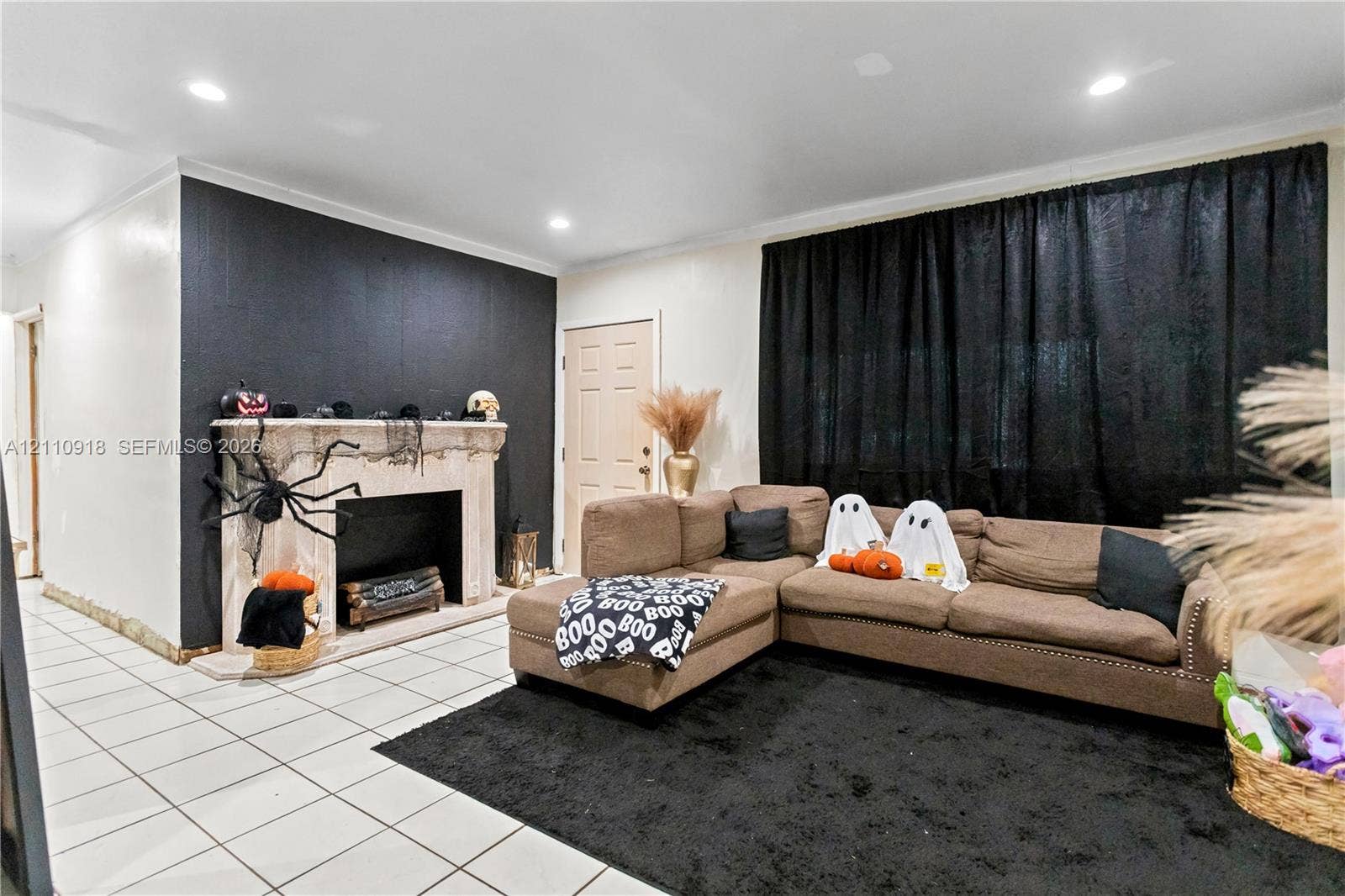 2007 NW 89th Street, Miami, FL 33147 Living area featuring neutral tile flooring, a fireplace with a decorative stone-finish mantle, recessed ceiling lighting, and a prominent black accent wall