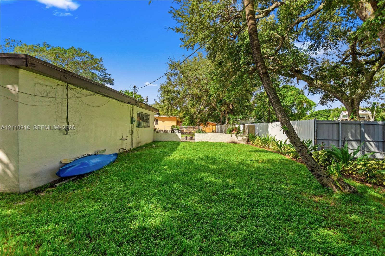 2007 NW 89th Street, Miami, FL 33147 Side yard featuring a grass lawn, mature trees, and perimeter fencing