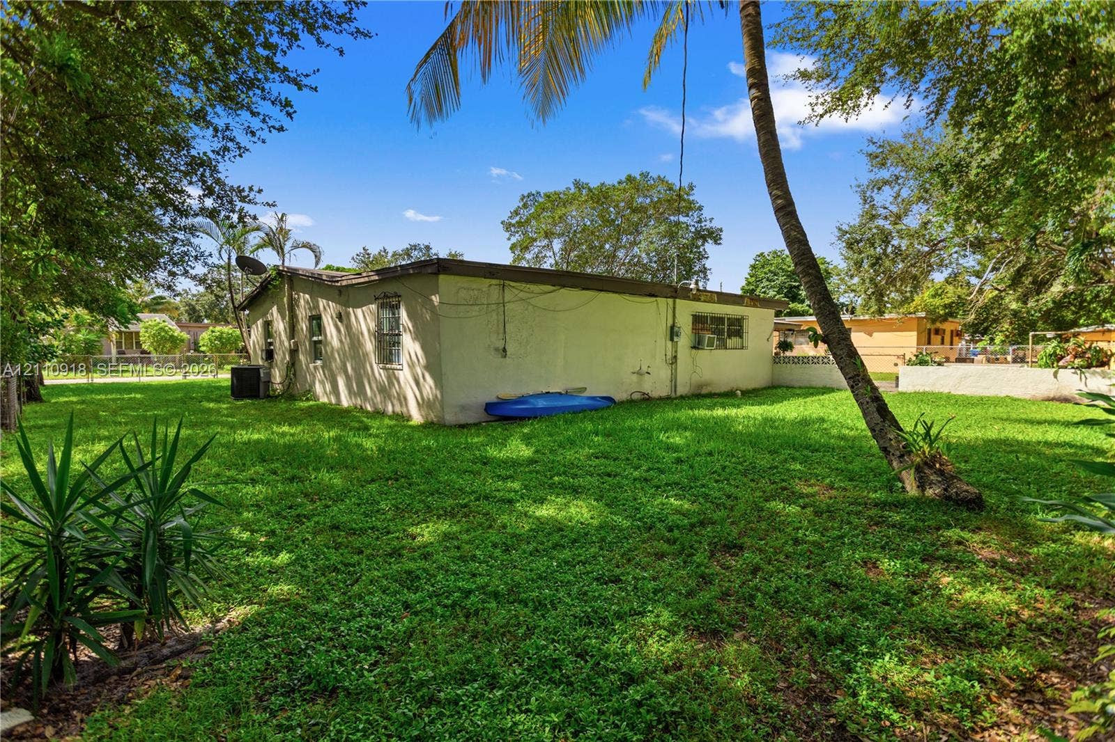 2007 NW 89th Street, Miami, FL 33147 Stucco exterior featuring mature landscaping, palm trees, and an expansive grass lawn