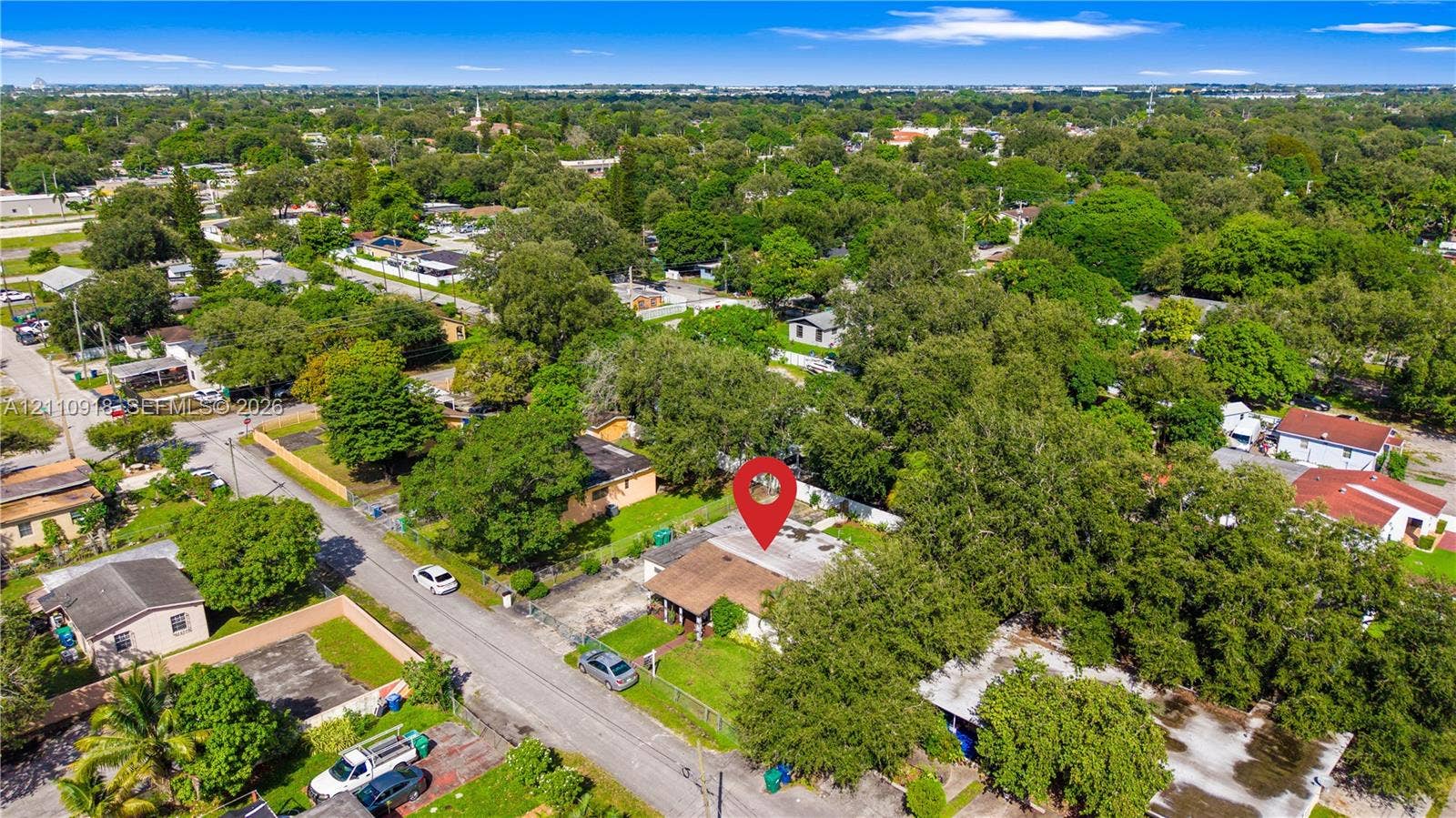 2007 NW 89th Street, Miami, FL 33147 Aerial perspective of property featuring a shingled roof, paved driveway, and established tree canopy