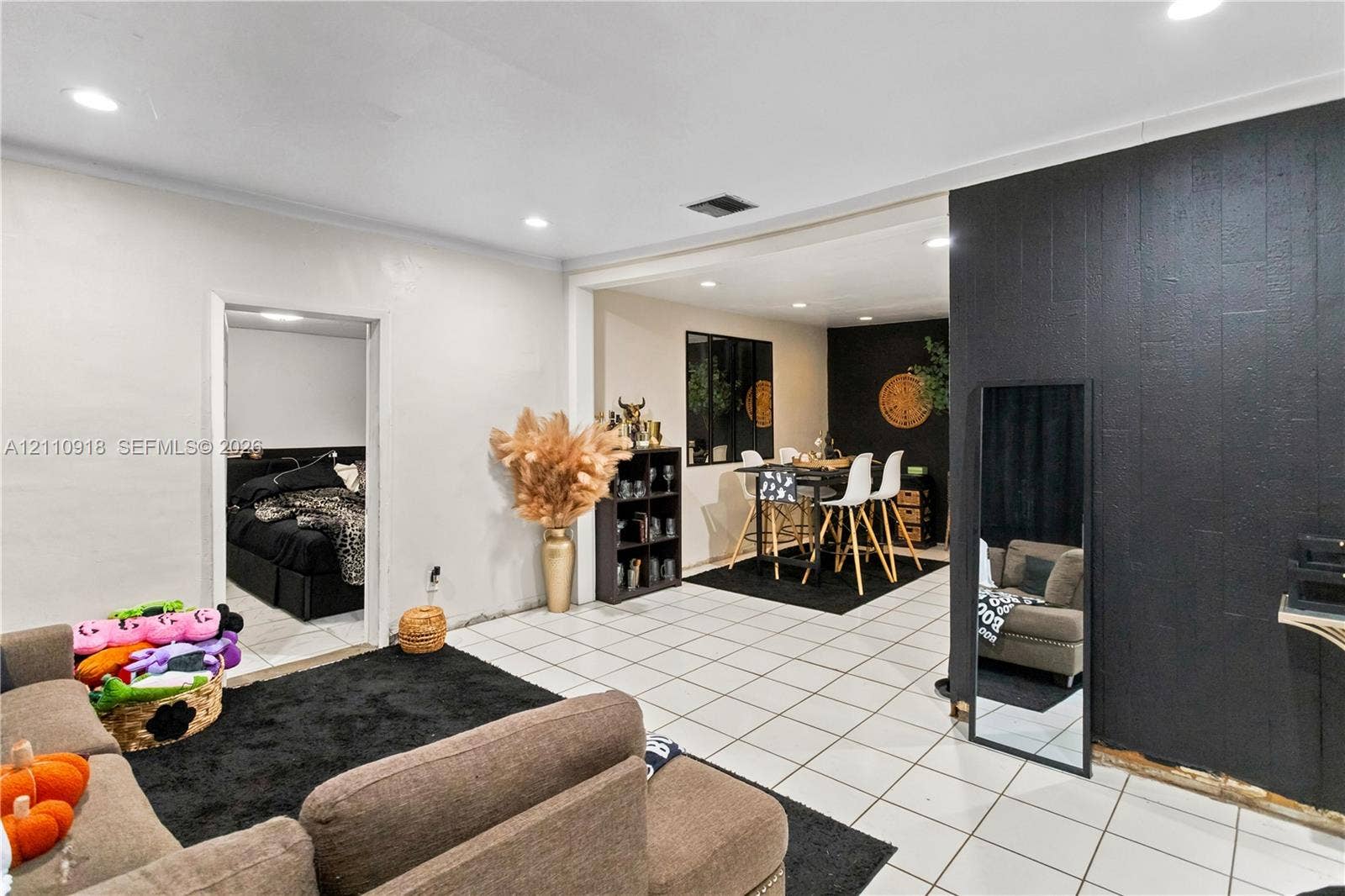 2007 NW 89th Street, Miami, FL 33147 Interior space featuring white ceramic tile flooring, recessed lighting, and a prominent black wood-textured accent wall