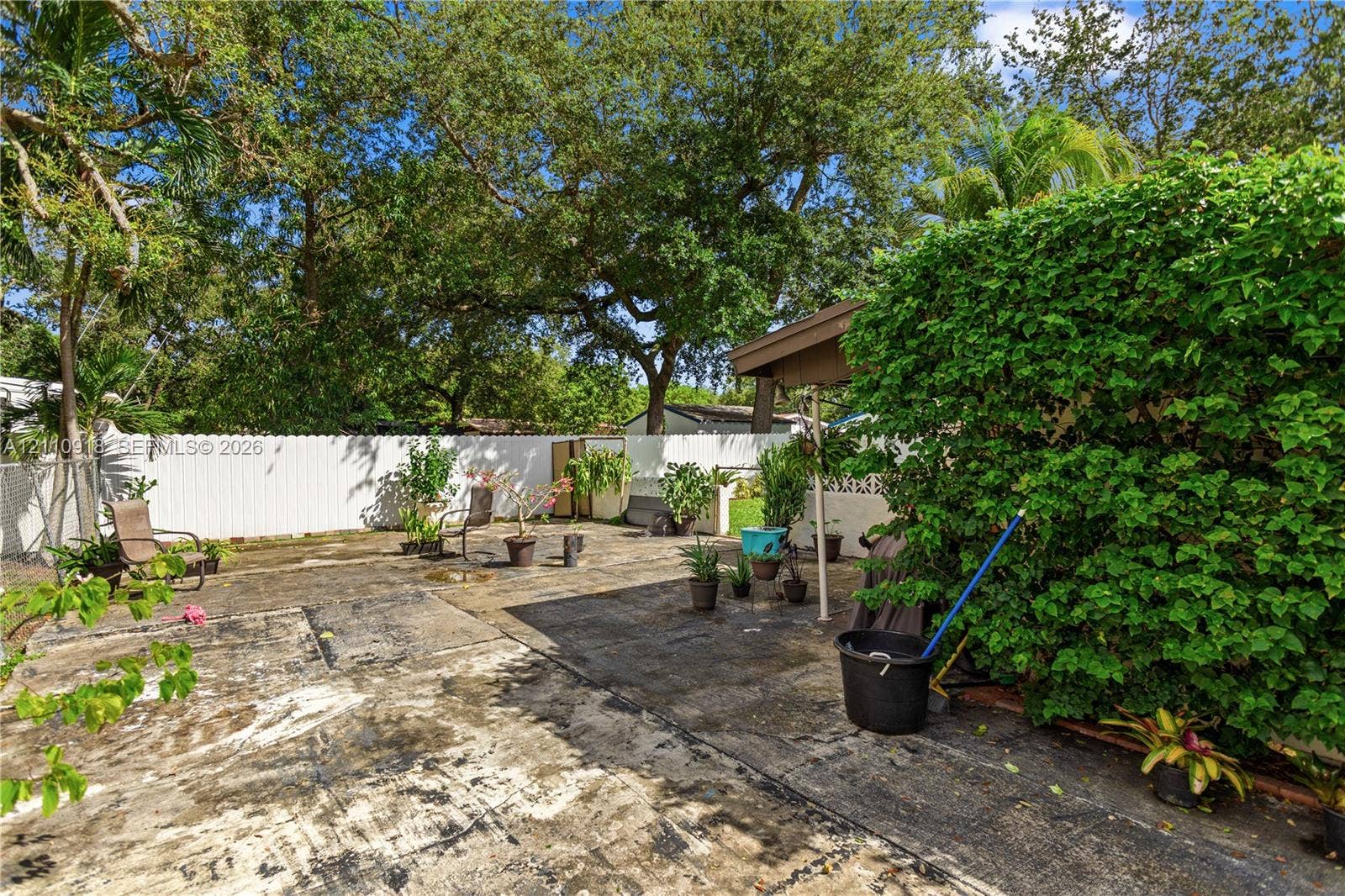 2007 NW 89th Street, Miami, FL 33147 Fenced backyard featuring a concrete patio, a covered structure, and mature trees