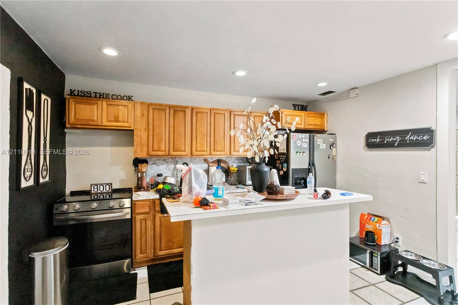 2007 NW 89th Street, Miami, FL 33147 Kitchen featuring light-finish cabinetry, a breakfast bar with a solid-surface countertop, recessed ceiling lighting, and tile flooring