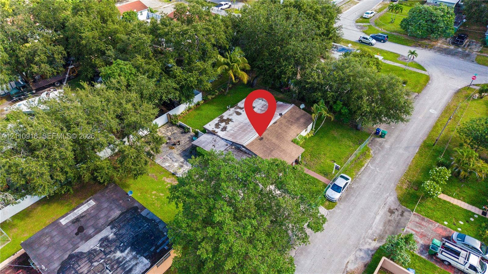 2007 NW 89th Street, Miami, FL 33147 Aerial perspective featuring a shingled roof, paved driveway, expansive lawn, and mature trees