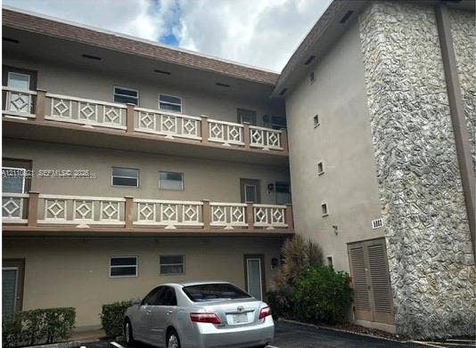 5003 NW 35th Street, #506, Lauderdale Lakes, Lauderdale Lakes, FL 33319 Three-story building exterior featuring textured stone masonry facade, multi-level balconies with geometric lattice railings, and exterior-access entry doors