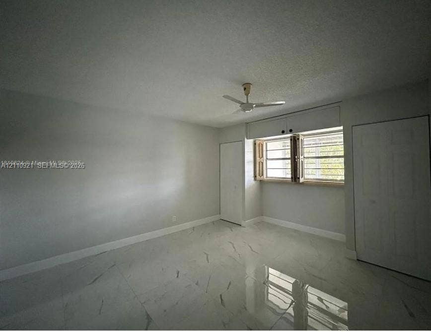 5003 NW 35th Street, #506, Lauderdale Lakes, Lauderdale Lakes, FL 33319 Large-format white tile flooring with grey veining, neutral-toned walls, a ceiling-mounted fan, and two built-in closets