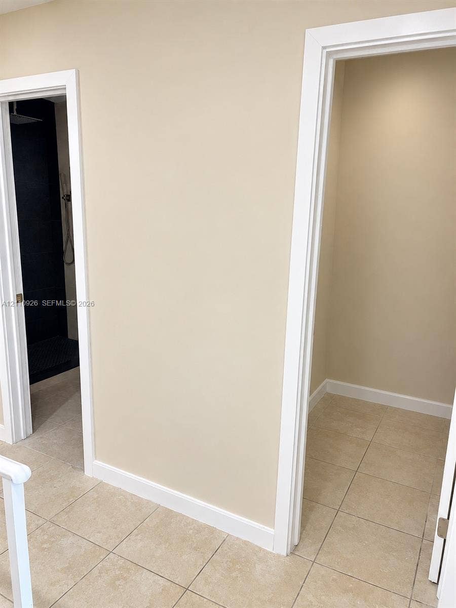 Tiled flooring, high-contrast dark interior shower wall, and minimalist casing trim