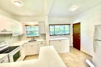 Kitchen featuring white cabinetry, solid-surface countertops, tile flooring, and multi-pane windows