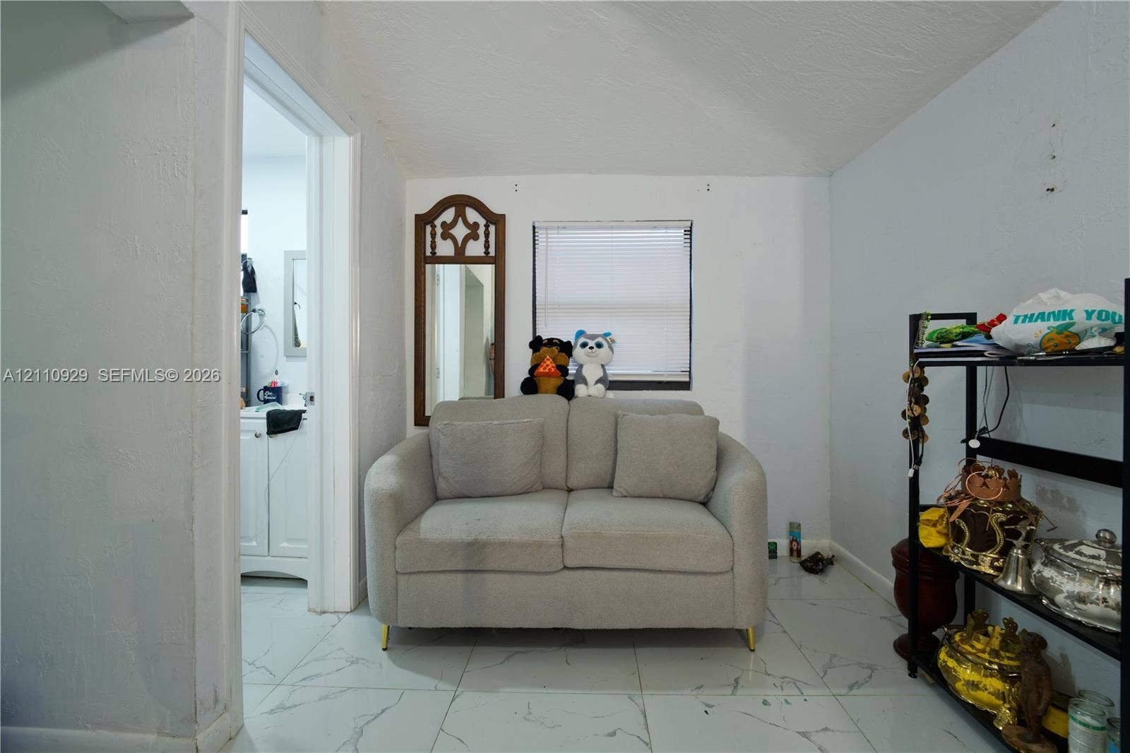 Neutral-toned wall finish with large-format, white, stone-patterned tile flooring and a rectangular window with horizontal blinds