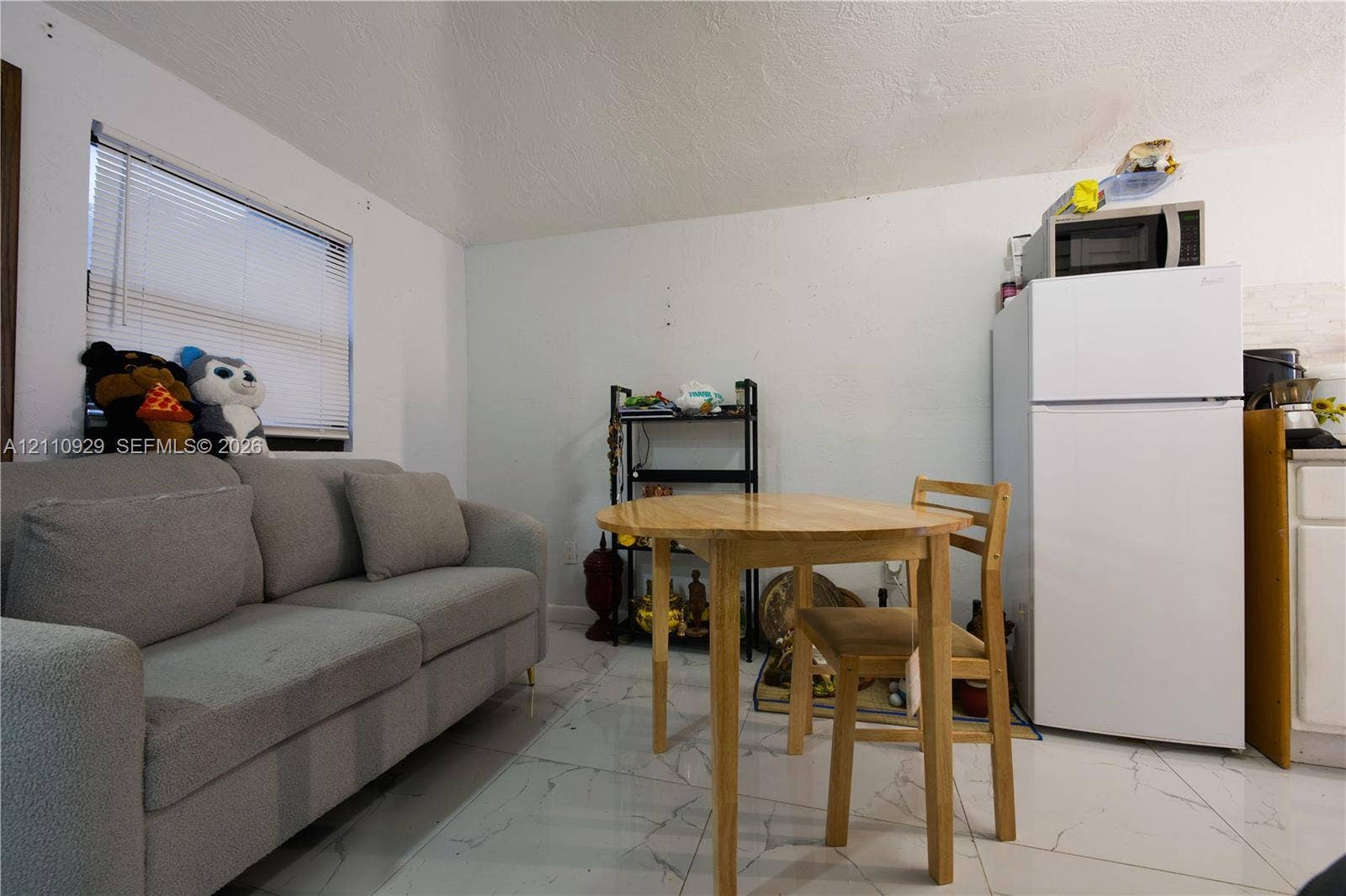 Light-filled interior featuring white large-format tile flooring and a horizontal window with integrated blinds