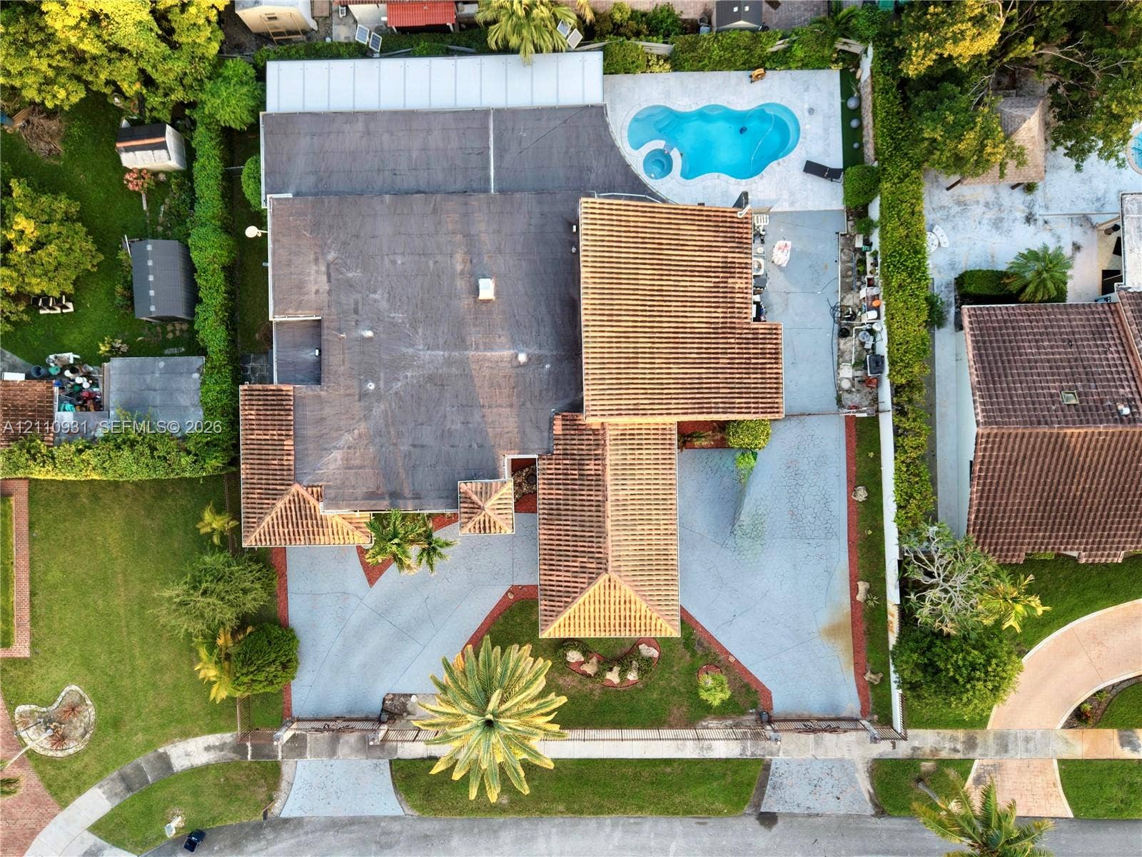3005 SW 99th Court, Miami, FL 33165 Aerial perspective featuring a tile roof, an in-ground swimming pool, a sprawling paved driveway, and mature landscaping