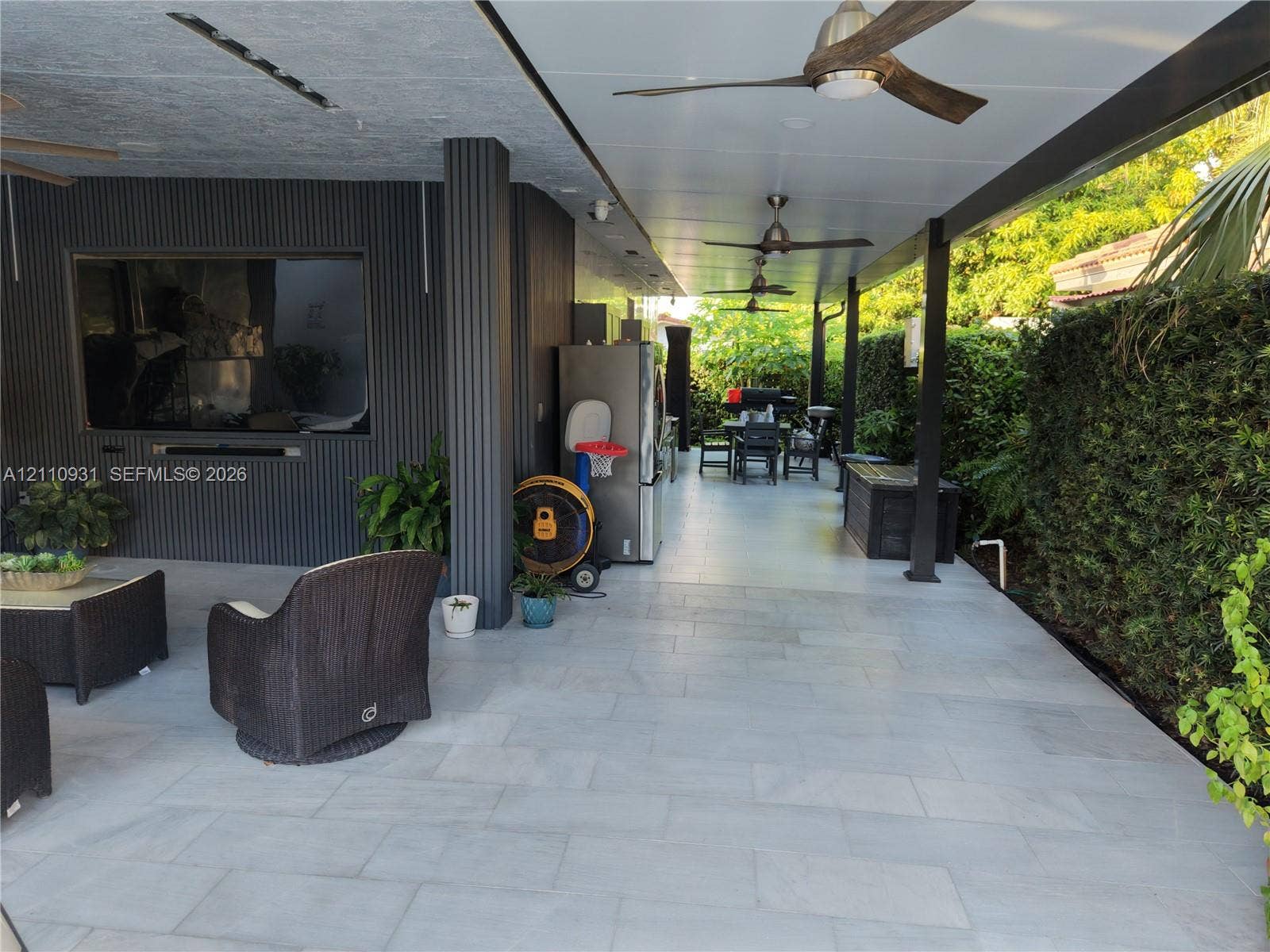 3005 SW 99th Court, Miami, FL 33165 Covered patio featuring large-format stone-style tile flooring, recessed ceiling lighting, multiple overhead fans, and vertical-slat wall accents