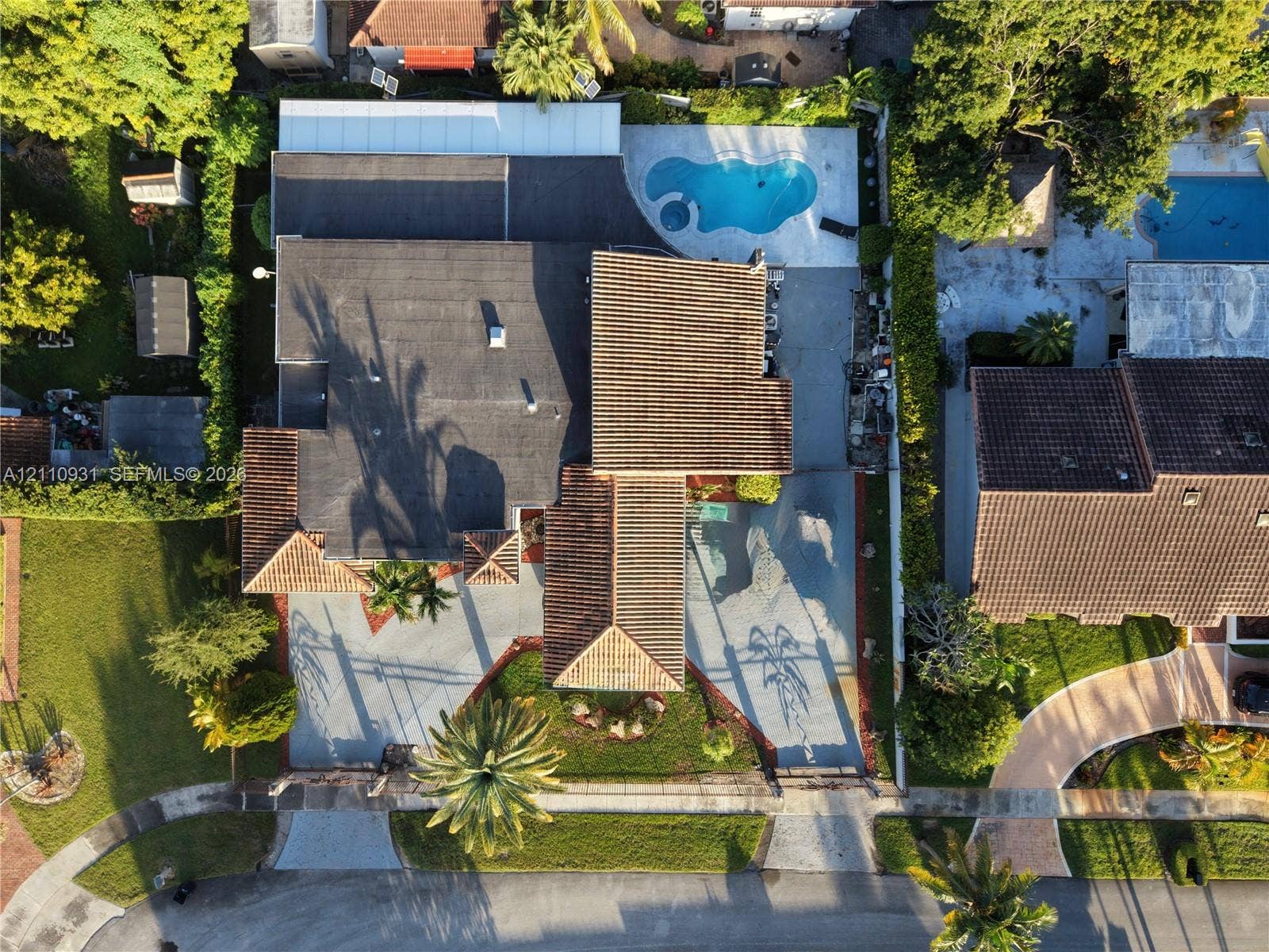 3005 SW 99th Court, Miami, FL 33165 Aerial perspective of a multi-section roofline, expansive concrete driveway, and backyard pool area with integrated hardscaping