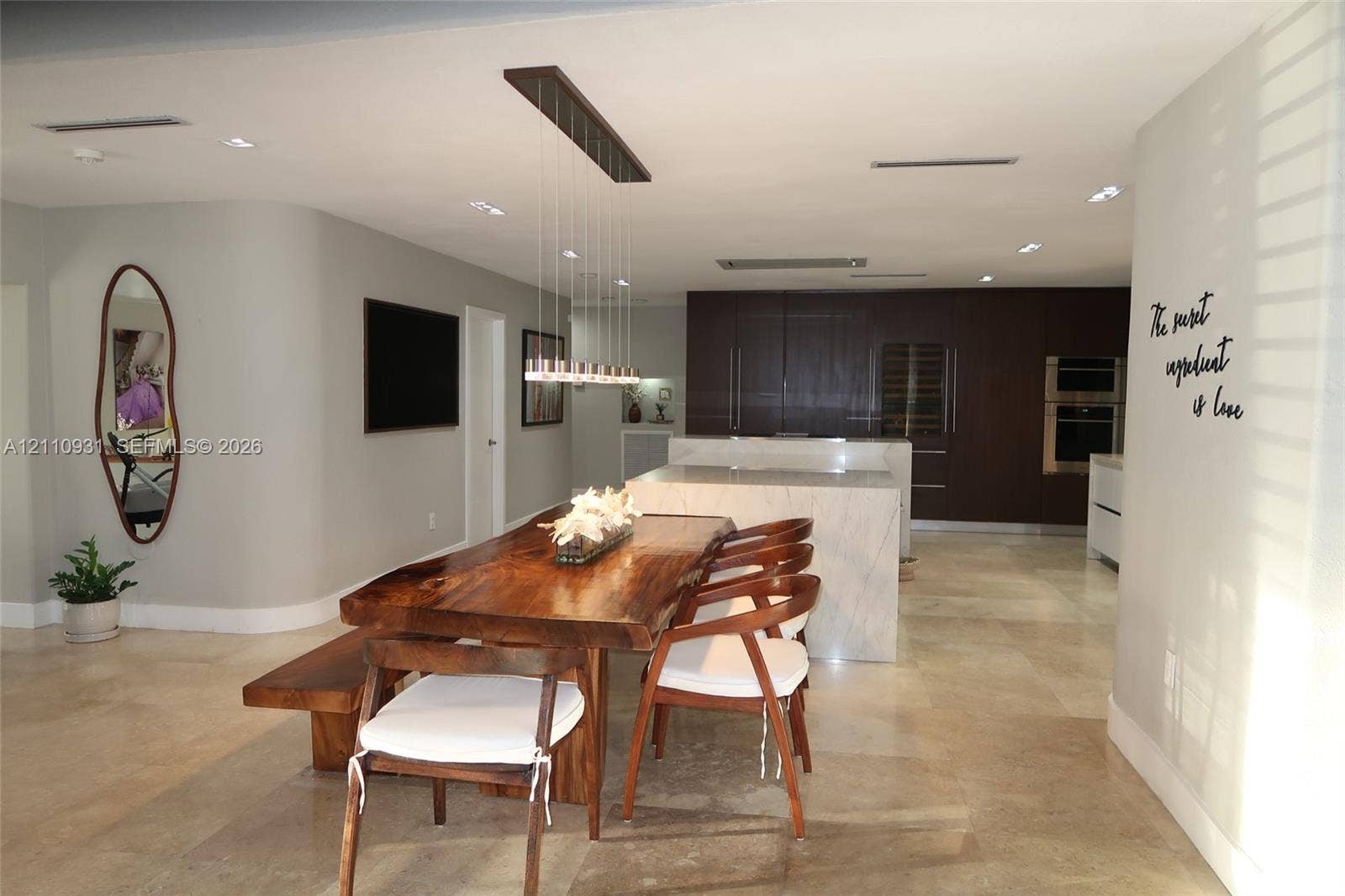 3005 SW 99th Court, Miami, FL 33165 Open-concept kitchen featuring dark wood cabinetry, integrated double wall ovens, built-in wine refrigeration, and a large stone-surfaced kitchen island, complemented by stone tile flooring and recessed ceiling lighting