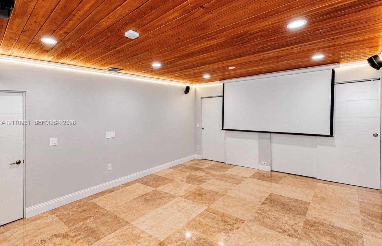 3005 SW 99th Court, Miami, FL 33165 Tongue-and-groove wood plank ceiling, recessed lighting, integrated perimeter accent lighting, wall-mounted projection screen, and polished stone flooring
