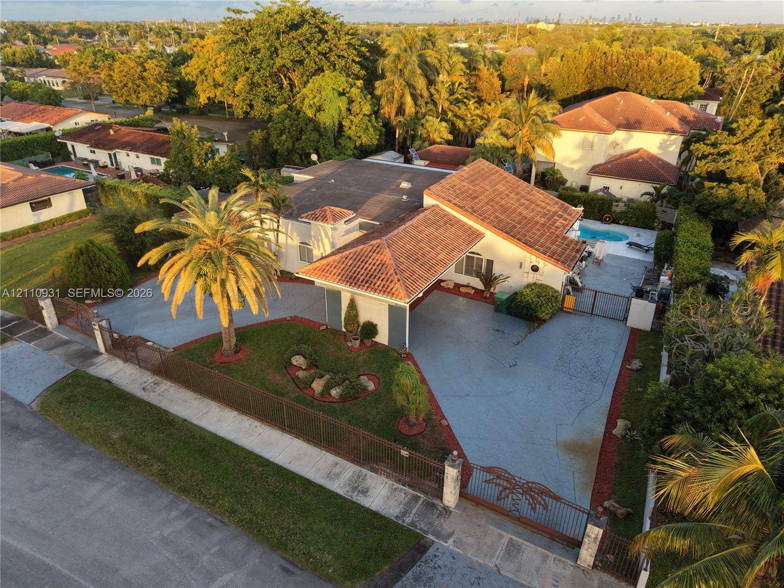 3005 SW 99th Court, Miami, FL 33165 Aerial perspective of a single-story residence featuring a terracotta-tiled roof, an integrated carport, a paved driveway, and an in-ground swimming pool