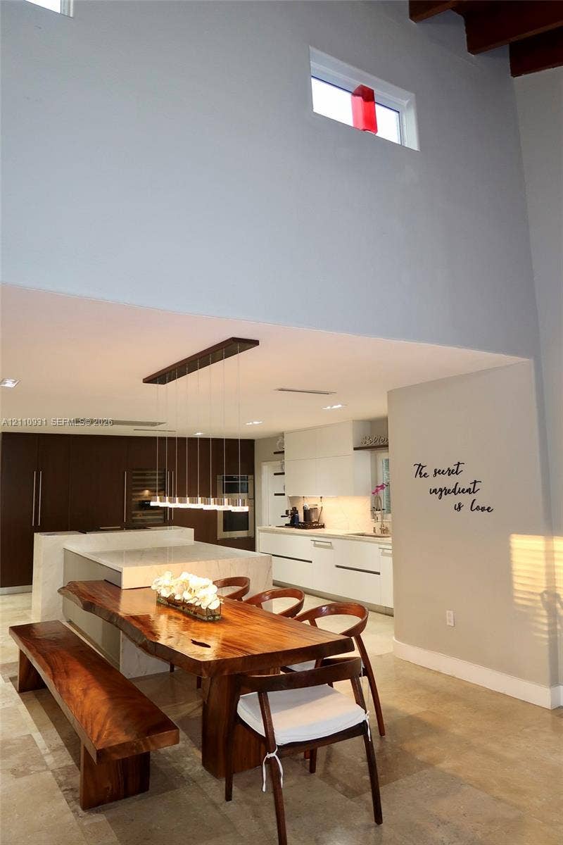 3005 SW 99th Court, Miami, FL 33165 Modern kitchen featuring flat-panel cabinetry, a central island with a stone-surface waterfall edge, high ceilings with exposed wood beams, clerestory windows, and recessed lighting