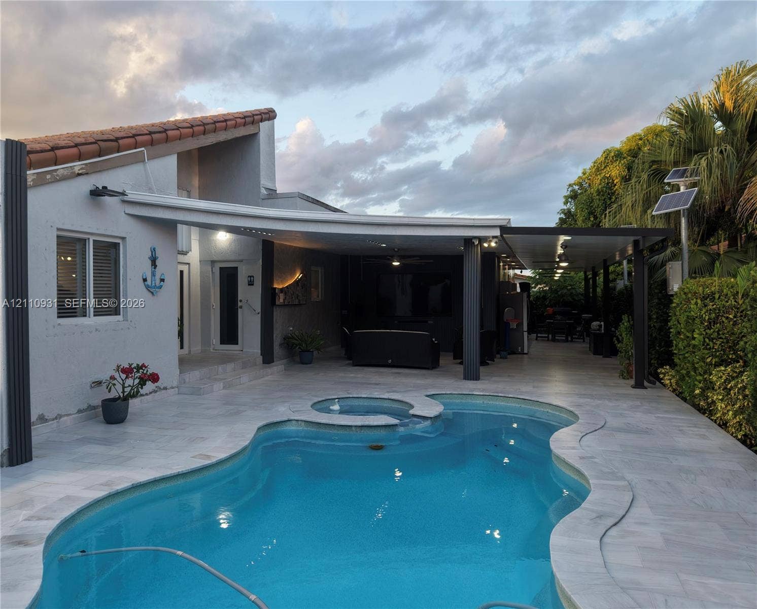 3005 SW 99th Court, Miami, FL 33165 In-ground swimming pool with integrated spa, covered patio area, recessed ceiling lighting, and exterior solar panels