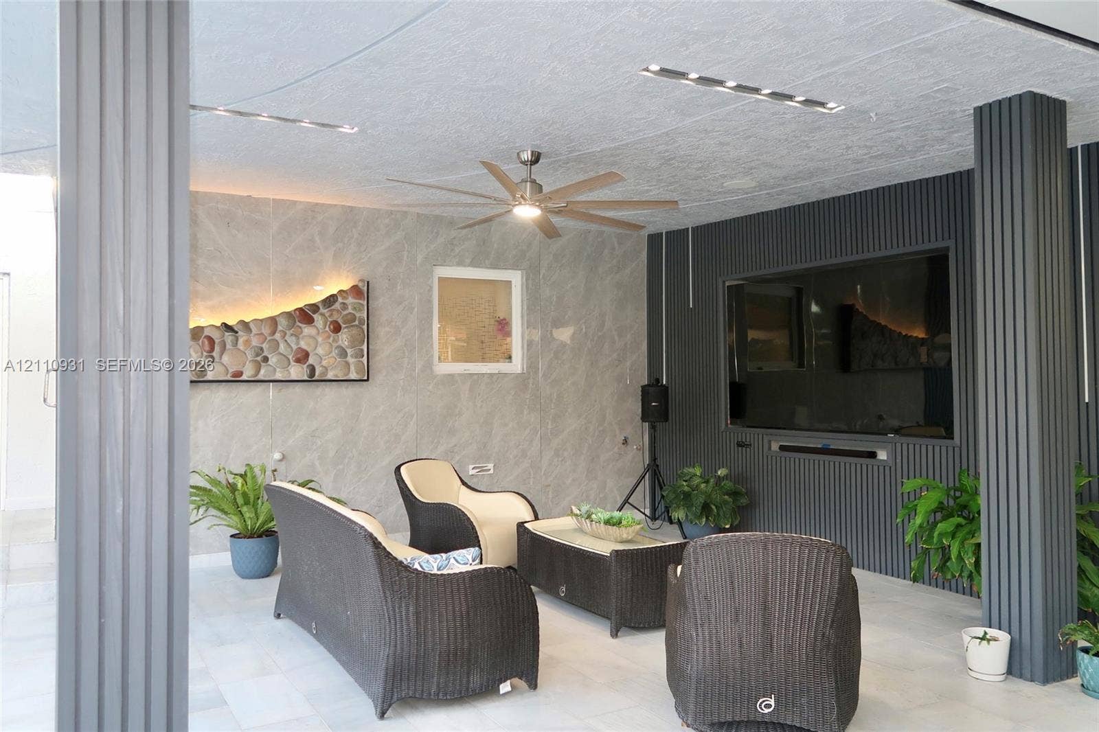 3005 SW 99th Court, Miami, FL 33165 Covered patio featuring large-format stone-finish wall tiling, vertical ribbed accent paneling, recessed ceiling lighting, and a ceiling fan