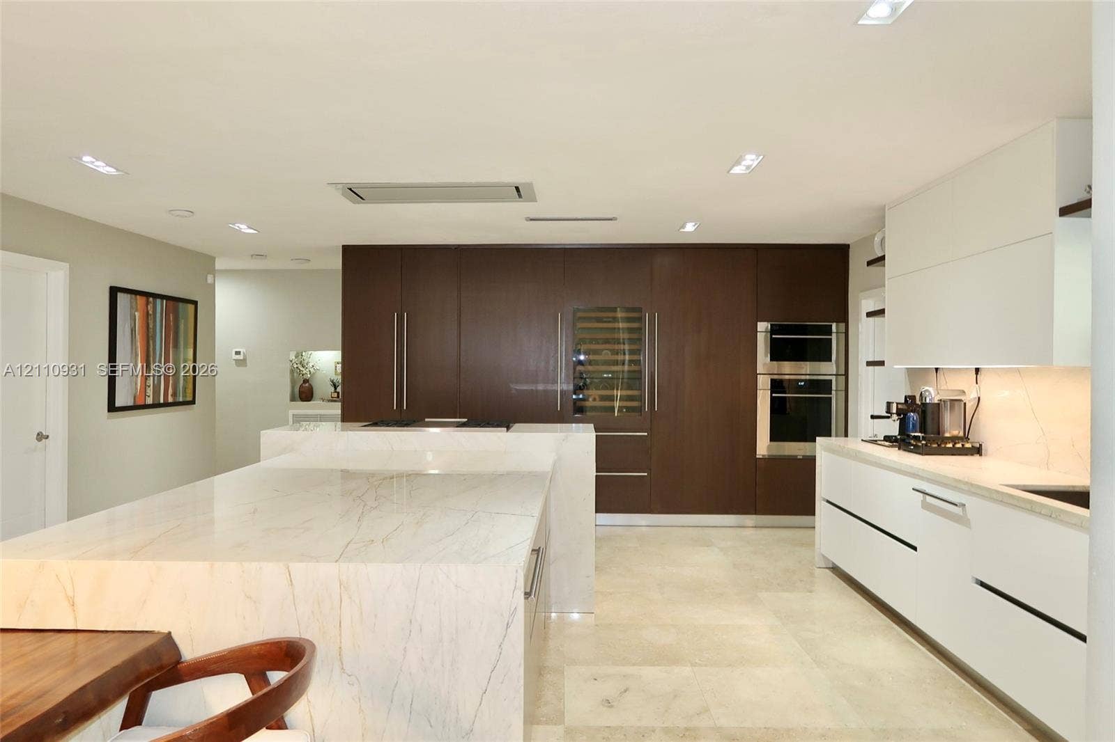 3005 SW 99th Court, Miami, FL 33165 Kitchen featuring stone-topped waterfall island, dark wood-finish cabinetry, built-in wine refrigeration, integrated wall ovens, and stone flooring