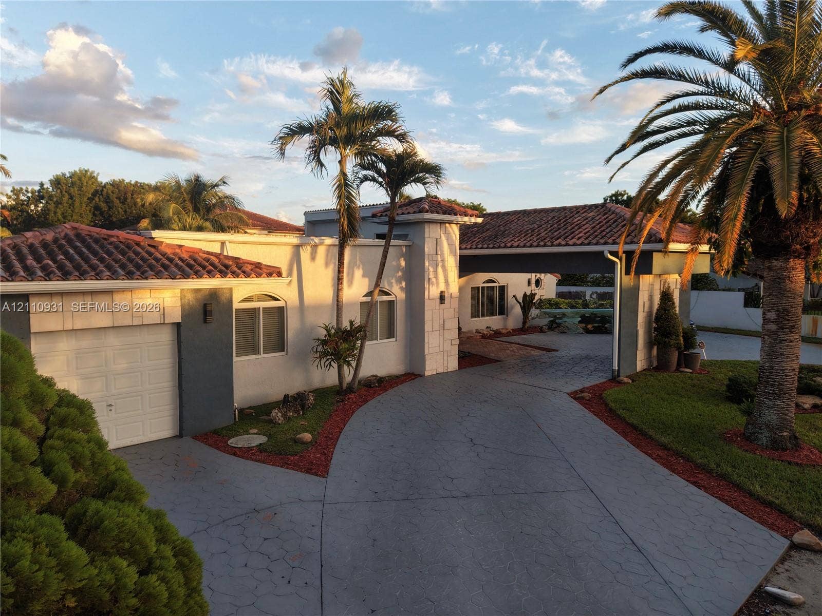 3005 SW 99th Court, Miami, FL 33165 Stucco exterior featuring arched windows, a multi-car covered porte-cochre, decorative stone accents, and a tile roof